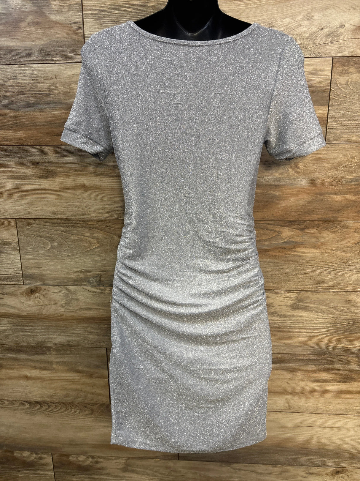 Shimmery silver short sleeve dress with ruched sides on wood background