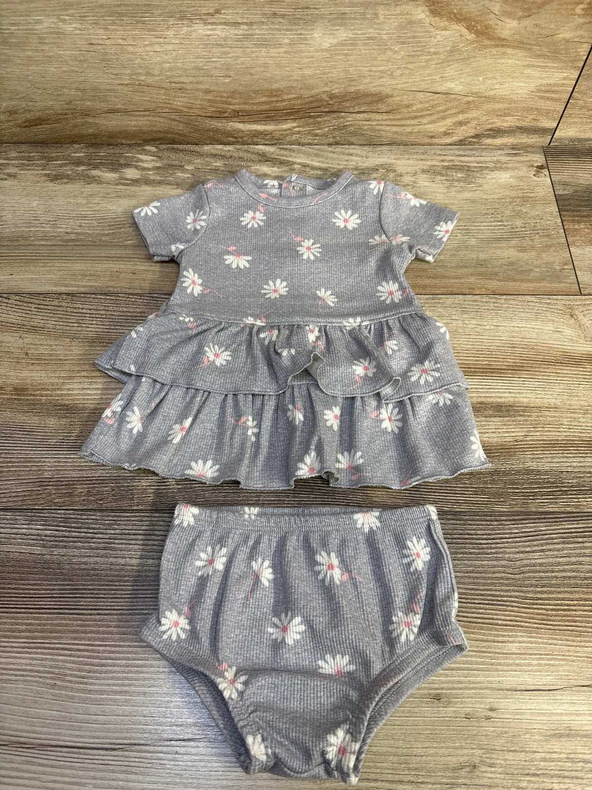 Front view of Modern Moments 2pc grey ribbed floral dress and matching bloomers showcasing tiered ruffles on a wood background