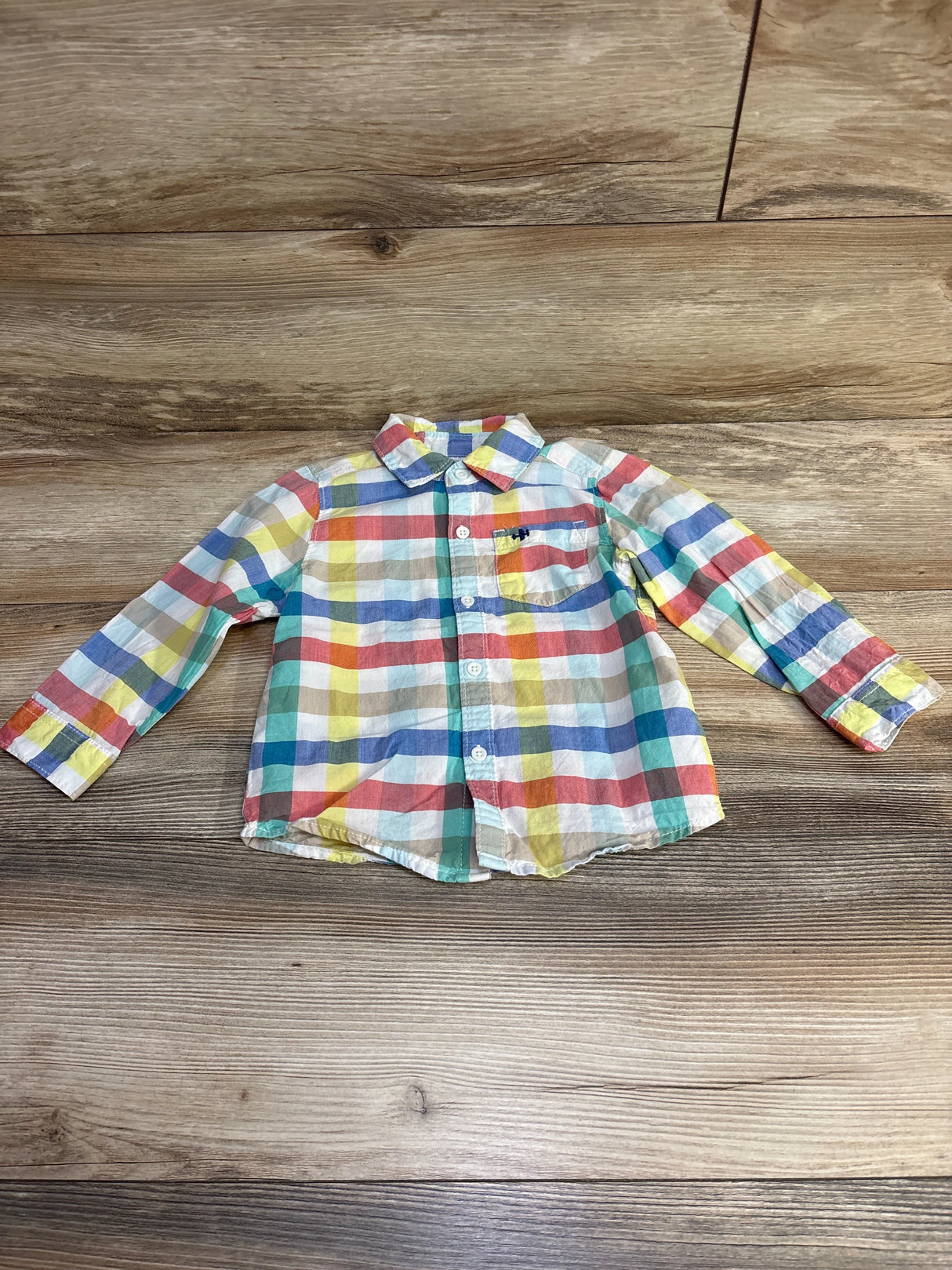 Colorful plaid long sleeve toddler shirt on wood background