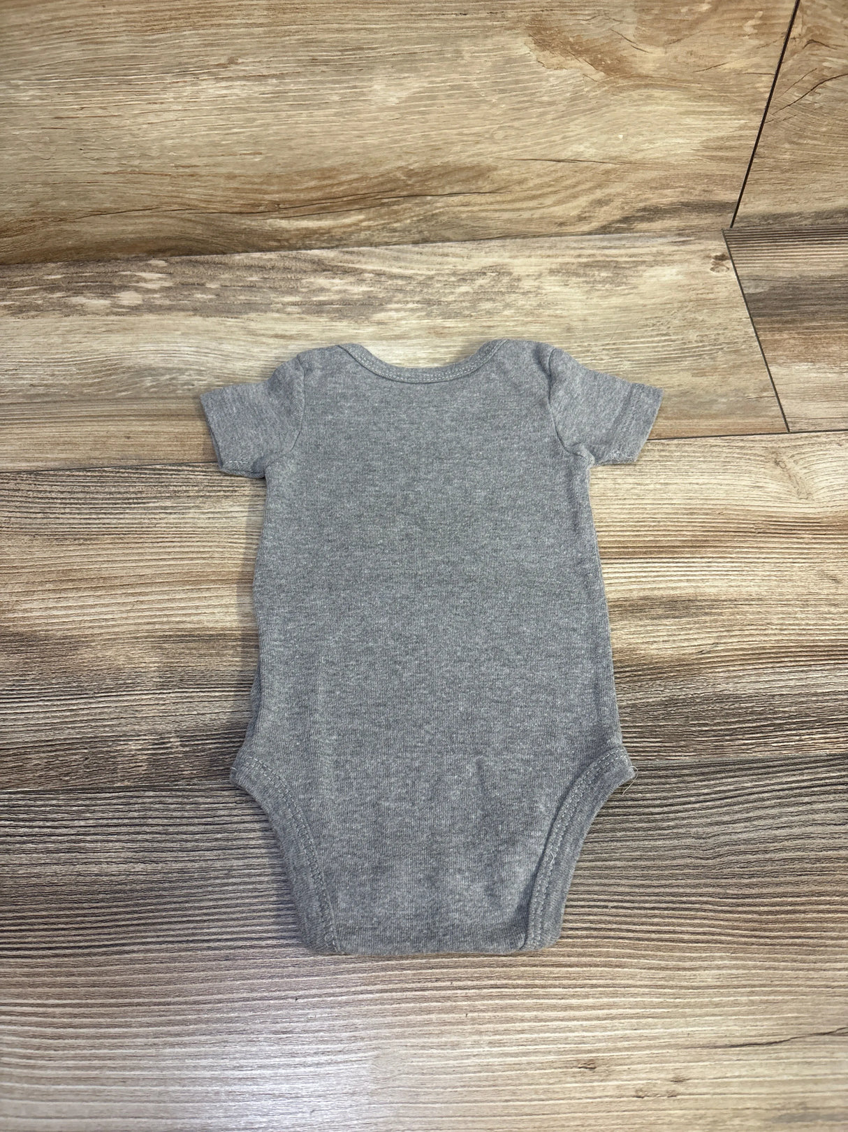 Flat-lay back view of grey Wiracle Wear baby bodysuit, short sleeves, heather knit fabric, size 3-6 months on wood background