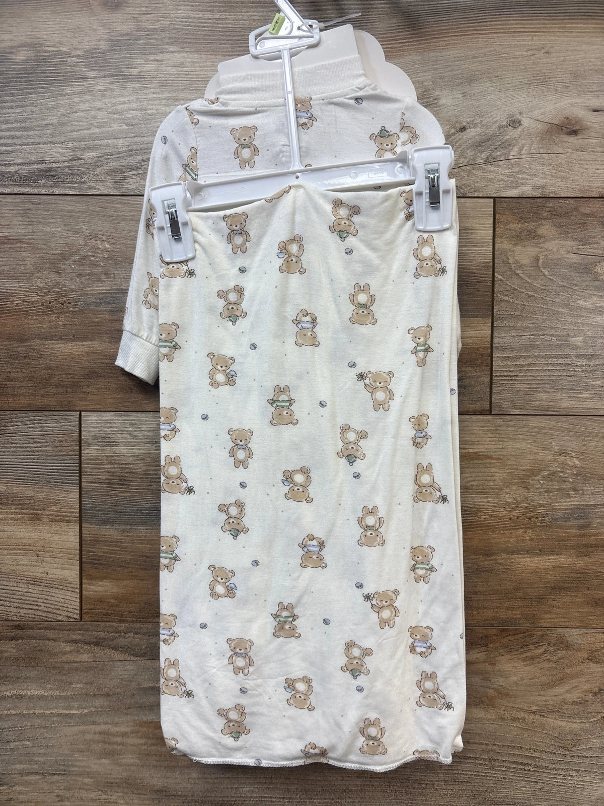 Front view of white four piece baby layette gift set in 3 month size showcasing teddy bear print on a wood background