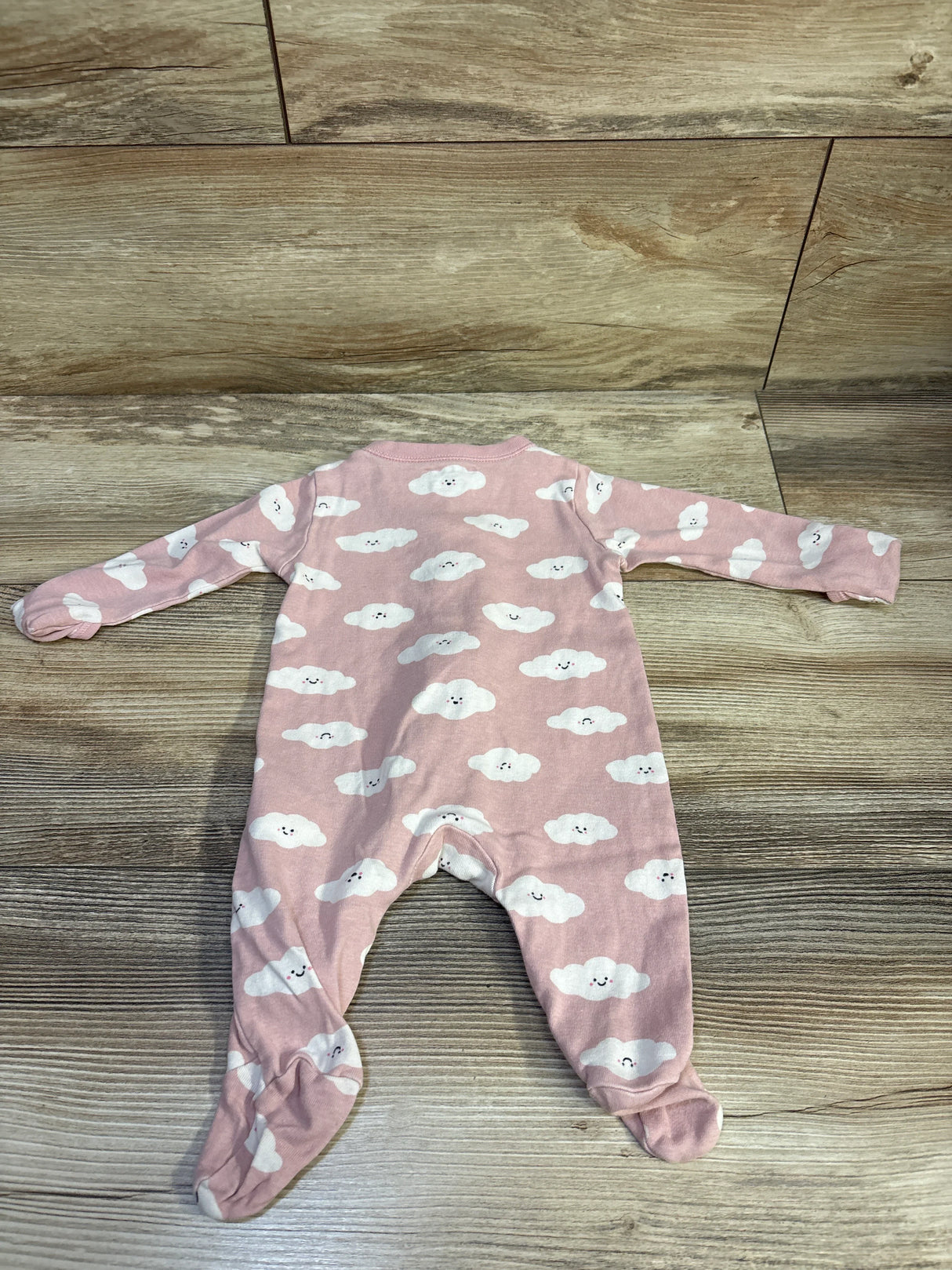 Flat-lay of pink Old Navy footed sleeper (0-3M) showing white smiling cloud print on wood background
