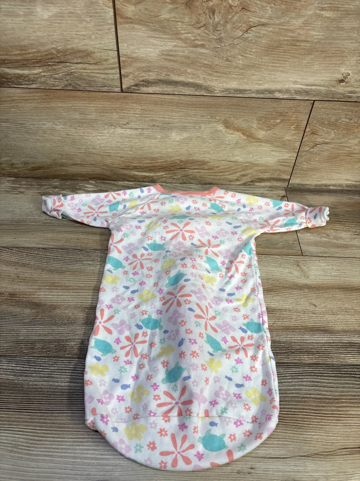 Top view of The Peanutshell sleep sack showcasing colorful floral print and long sleeves on a wood floor