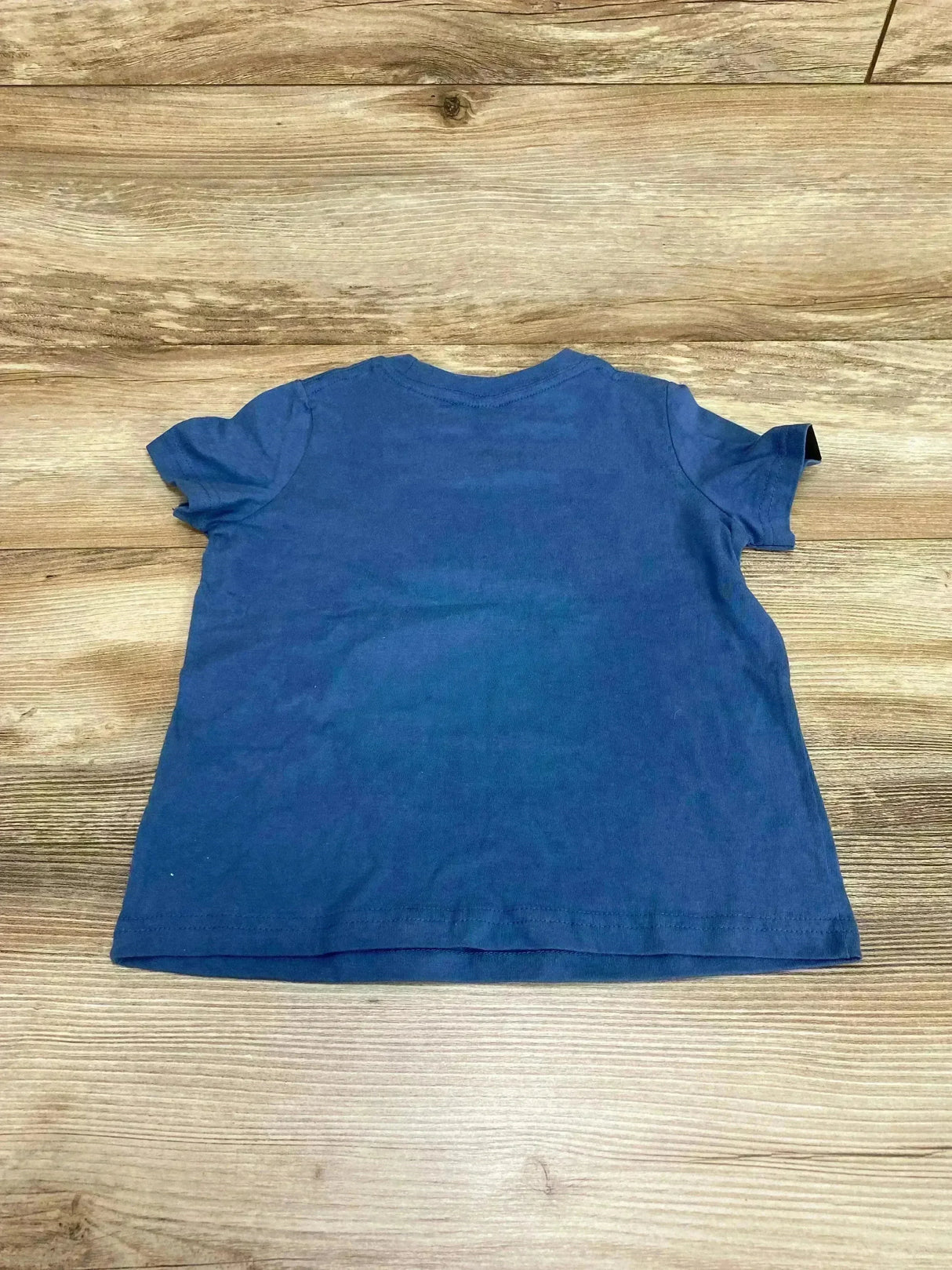 Back view of Aloha Made Fish and Poi tee in blue size 4T, short sleeves and crew neck, laid flat on wood