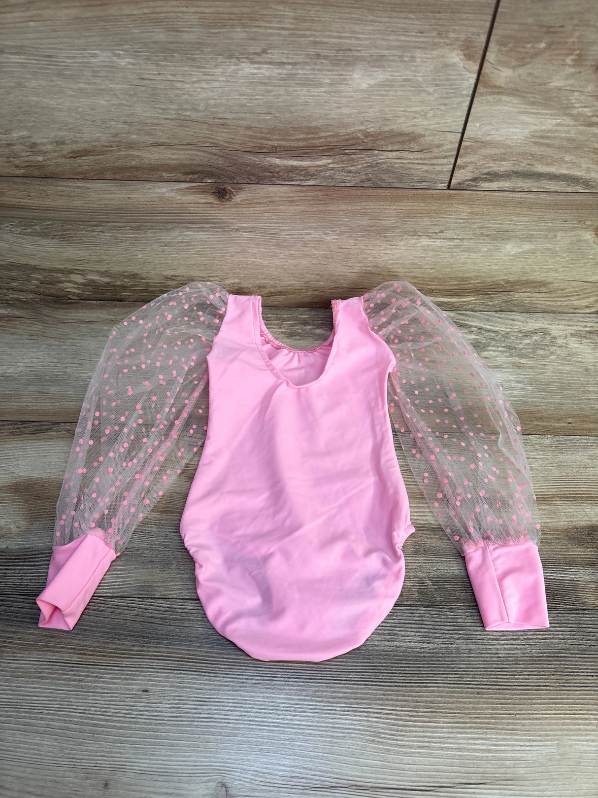 Pink baby onesie with sheer polka dot tulle sleeves, perfect for infant clothing or baby gear