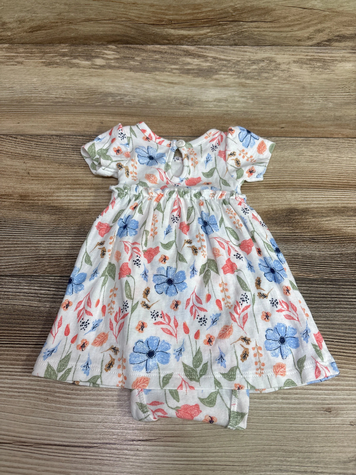 White preemie floral bodysuit dress from Me n Mommy To Be on a wooden background