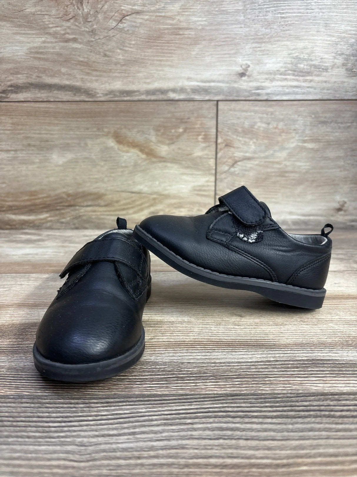 Angled view of Wonder Nation Oxford toddler dress shoes size 7C showing black leather upper and Velcro straps on wood floor