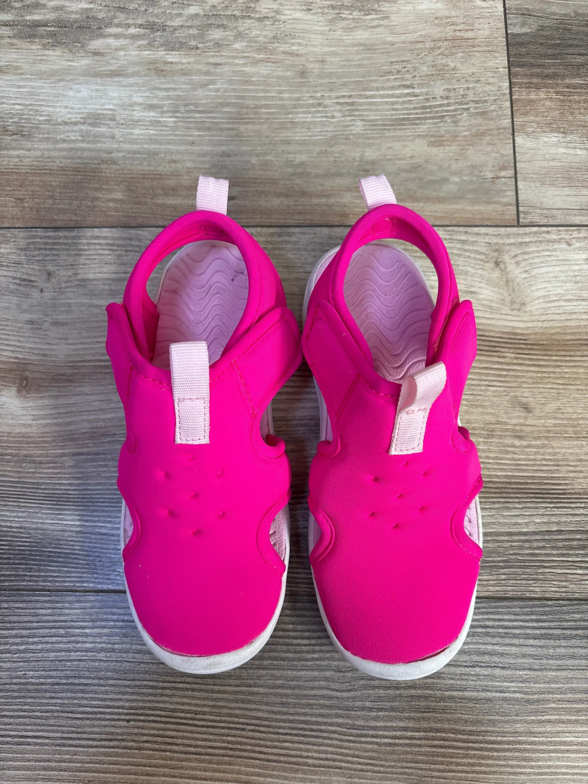 Top view of Cat & Jack Speedo water sandals, size 12C, showcasing pink uppers and hook and loop straps on wood-grain floor