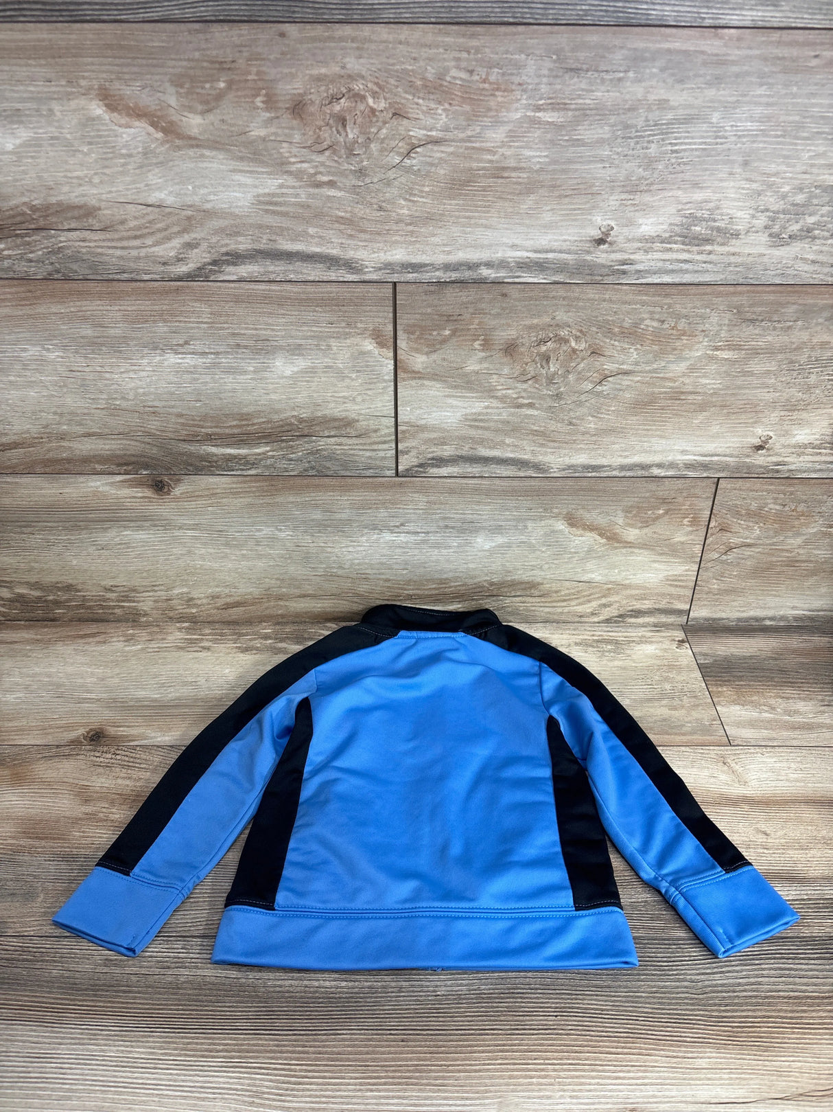 Blue and black long-sleeve kids jacket laid flat on wooden surface, children's clothing resale