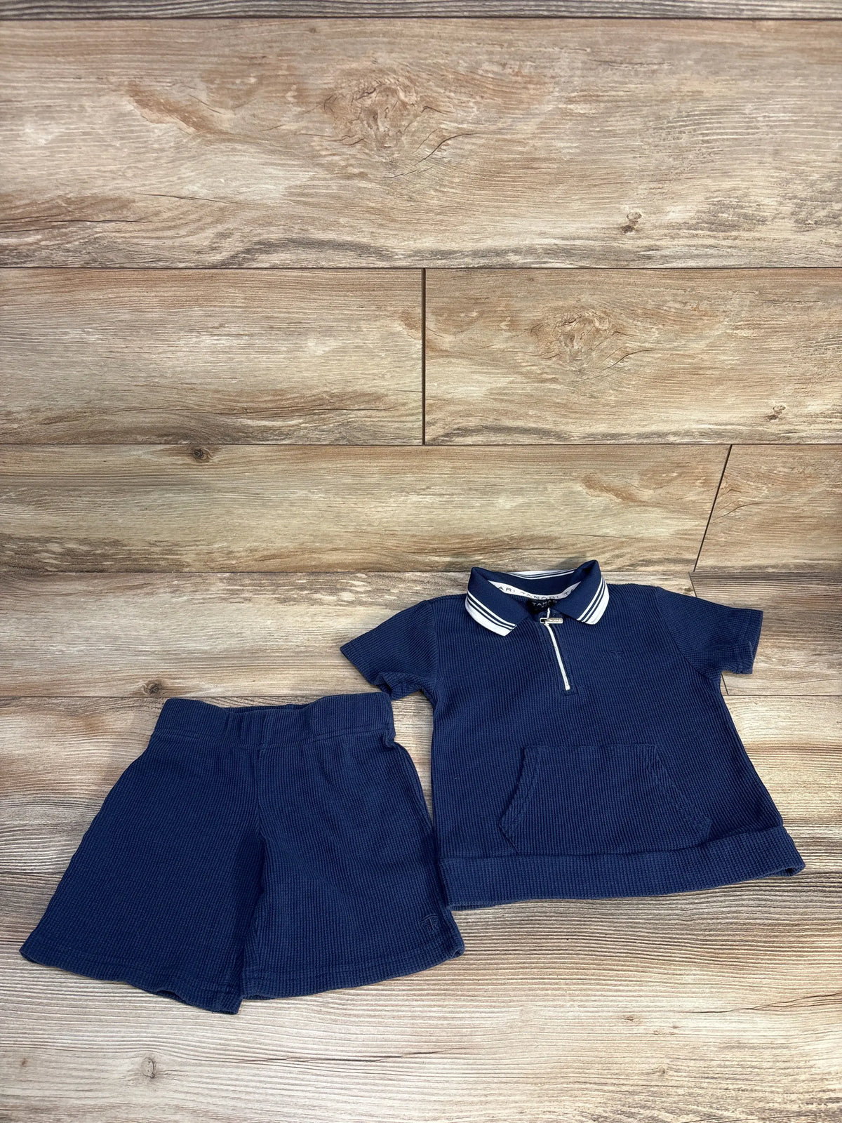 Front view of Tahari navy waffle knit quarter-zip shirt and matching shorts set showcasing striped collar and front pockets on a wood background