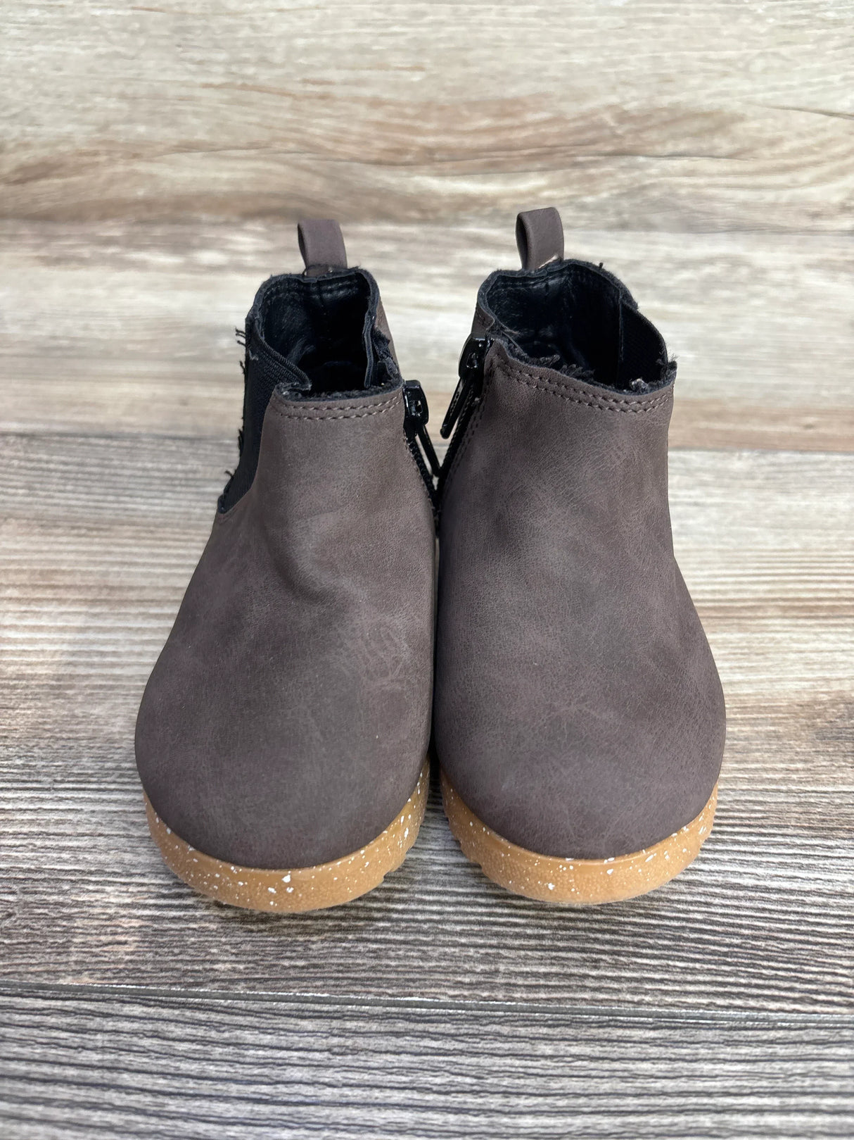 Pair of brown toddler boots with tan speckled soles on wooden surface