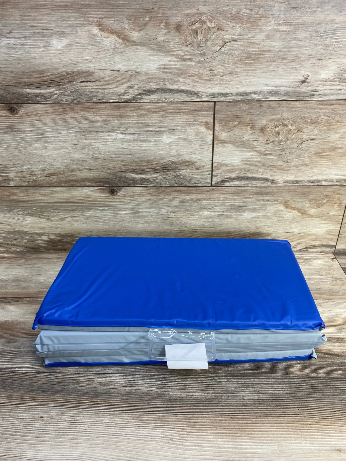 Folded view of ProSource Four-Fold Kids Rest Nap Mat showcasing blue waterproof vinyl covering and gray sides on a wood floor
