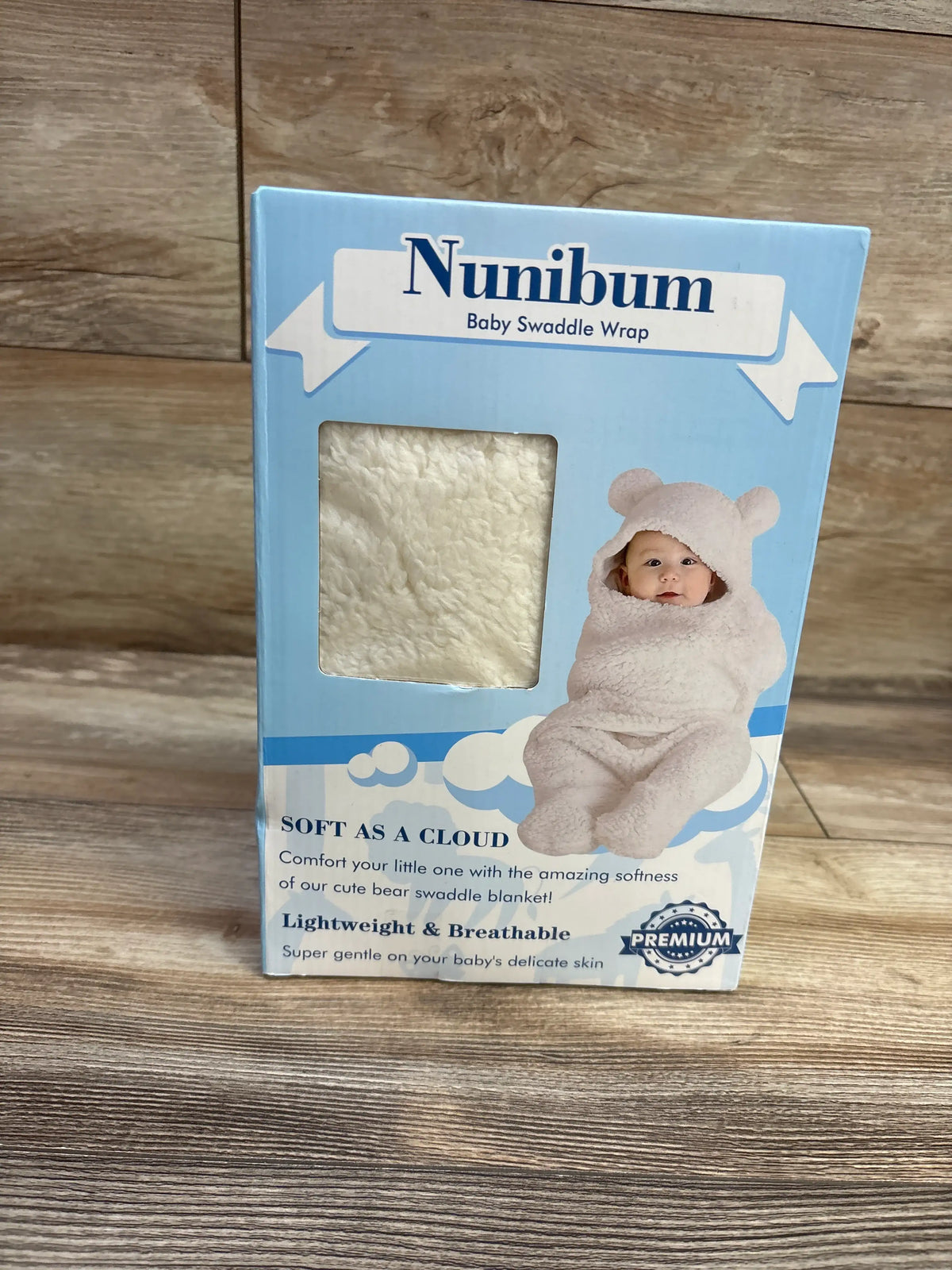 Front view of NuniBum sherpa swaddle wrap packaging showcasing ivory textured fabric and bear-ear hood