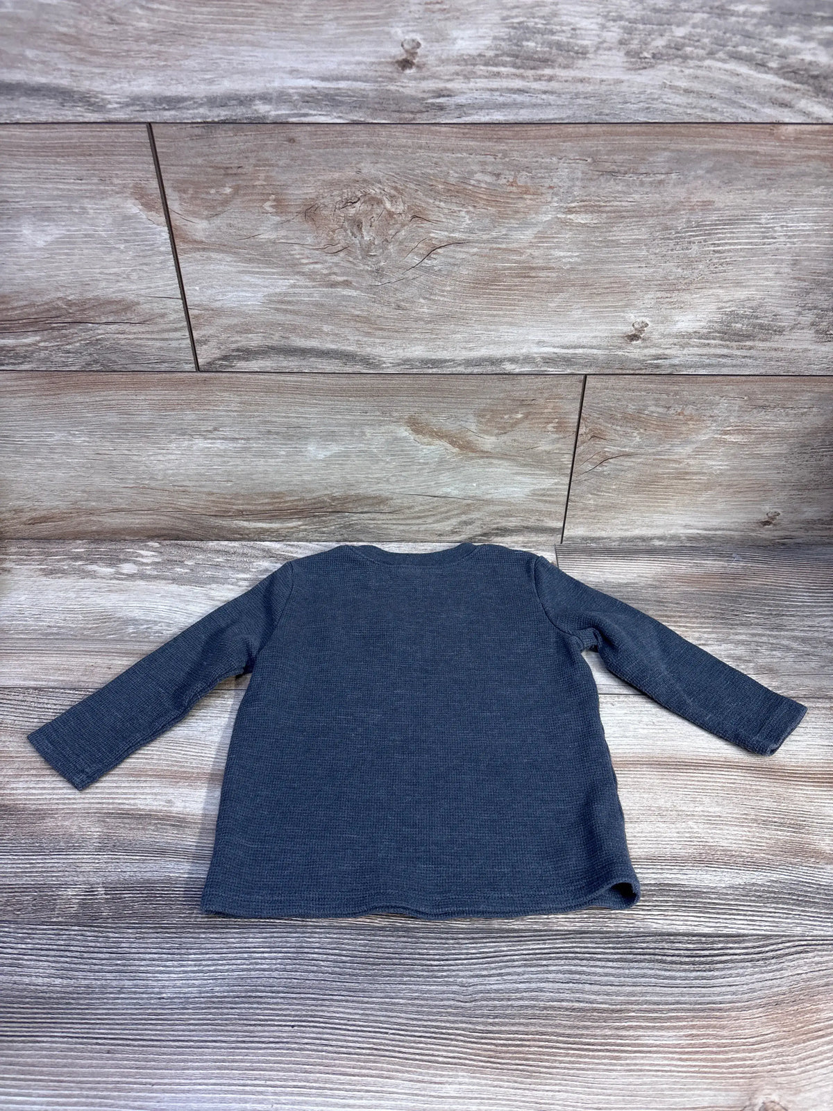 Overhead view of Jumping Beans Waffle Knit Shirt in grey showcasing long sleeves and textured fabric on a wood-grain background