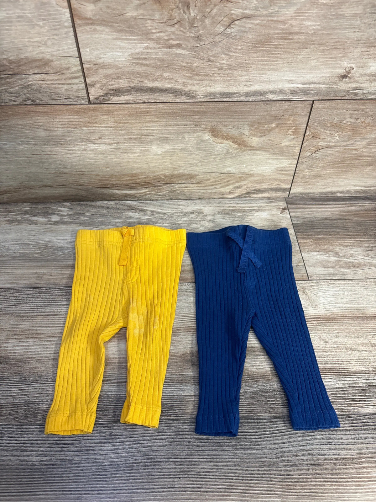 Top view of Koala Baby ribbed pants two-pack showcasing navy and yellow colors, ribbed legs, and drawstring waists