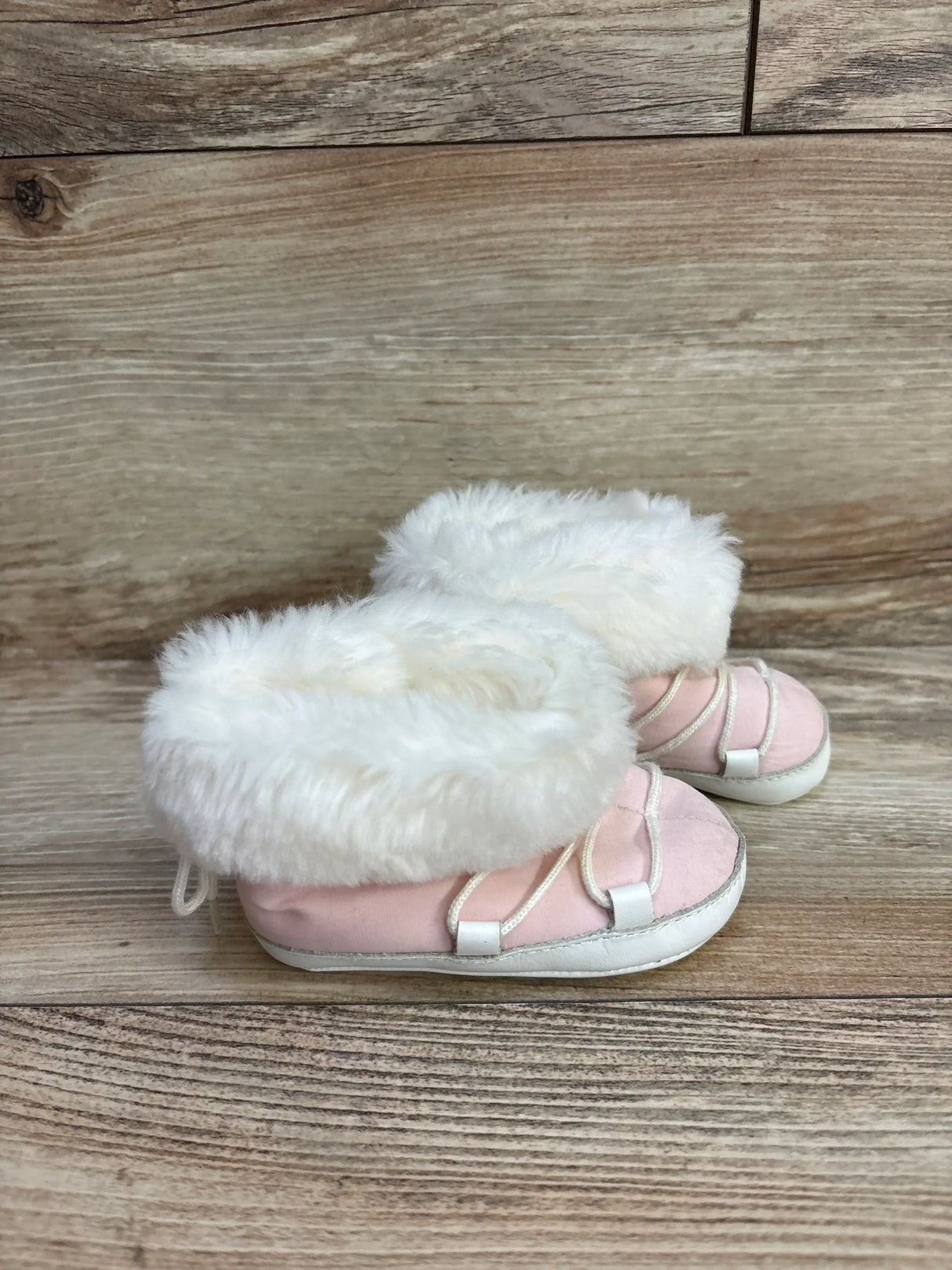 Side view of Janie and Jack pink faux-fur soft-sole winter boots showcasing white faux-fur cuff and elastic straps on wooden background, size 3C