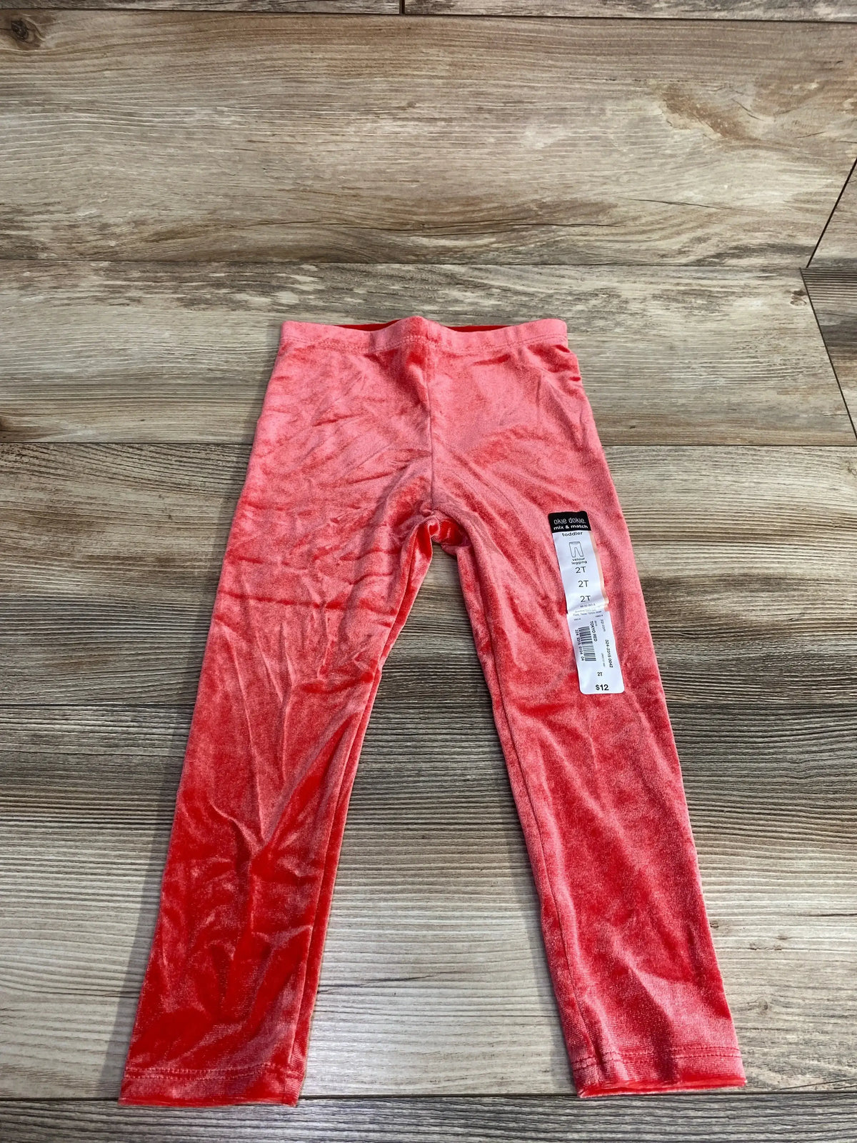 Flat lay of red velour toddler leggings size 2T showcasing soft velour fabric on wood floor