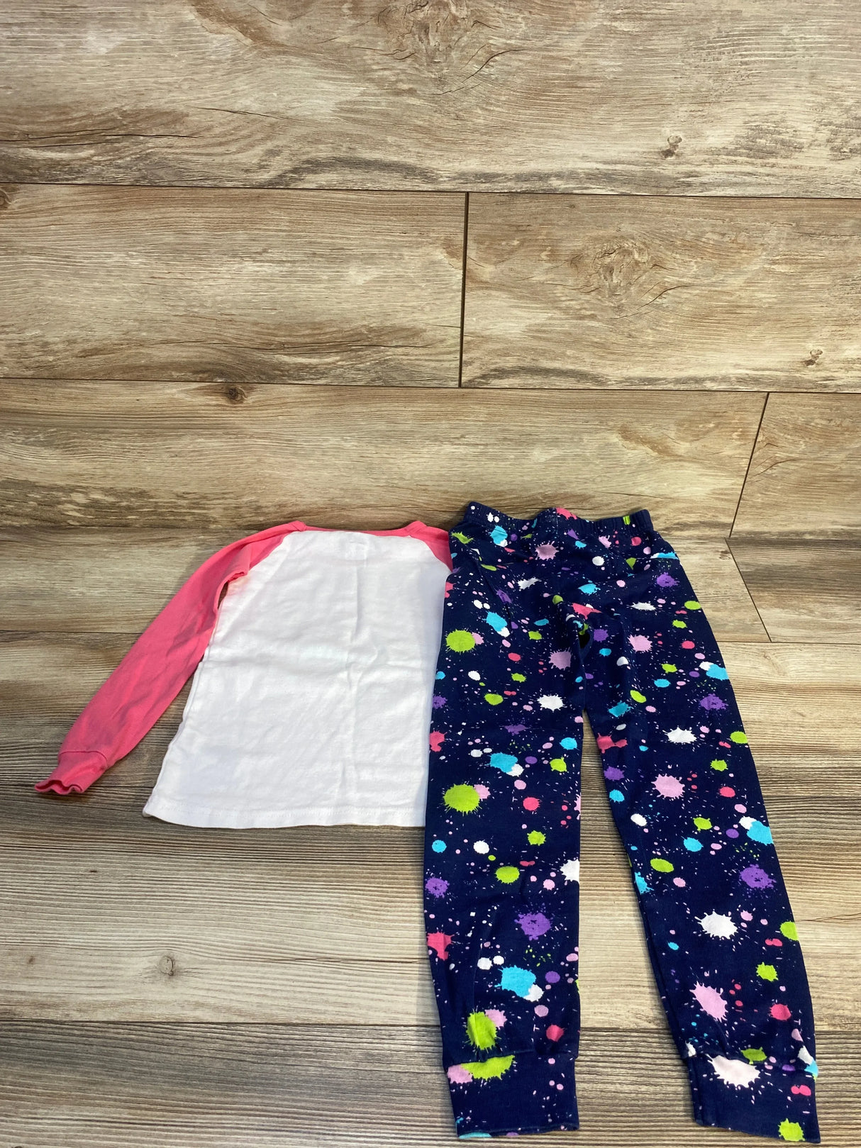 Kids outfit with pink and white long sleeve shirt and navy splatter print leggings on wood floor