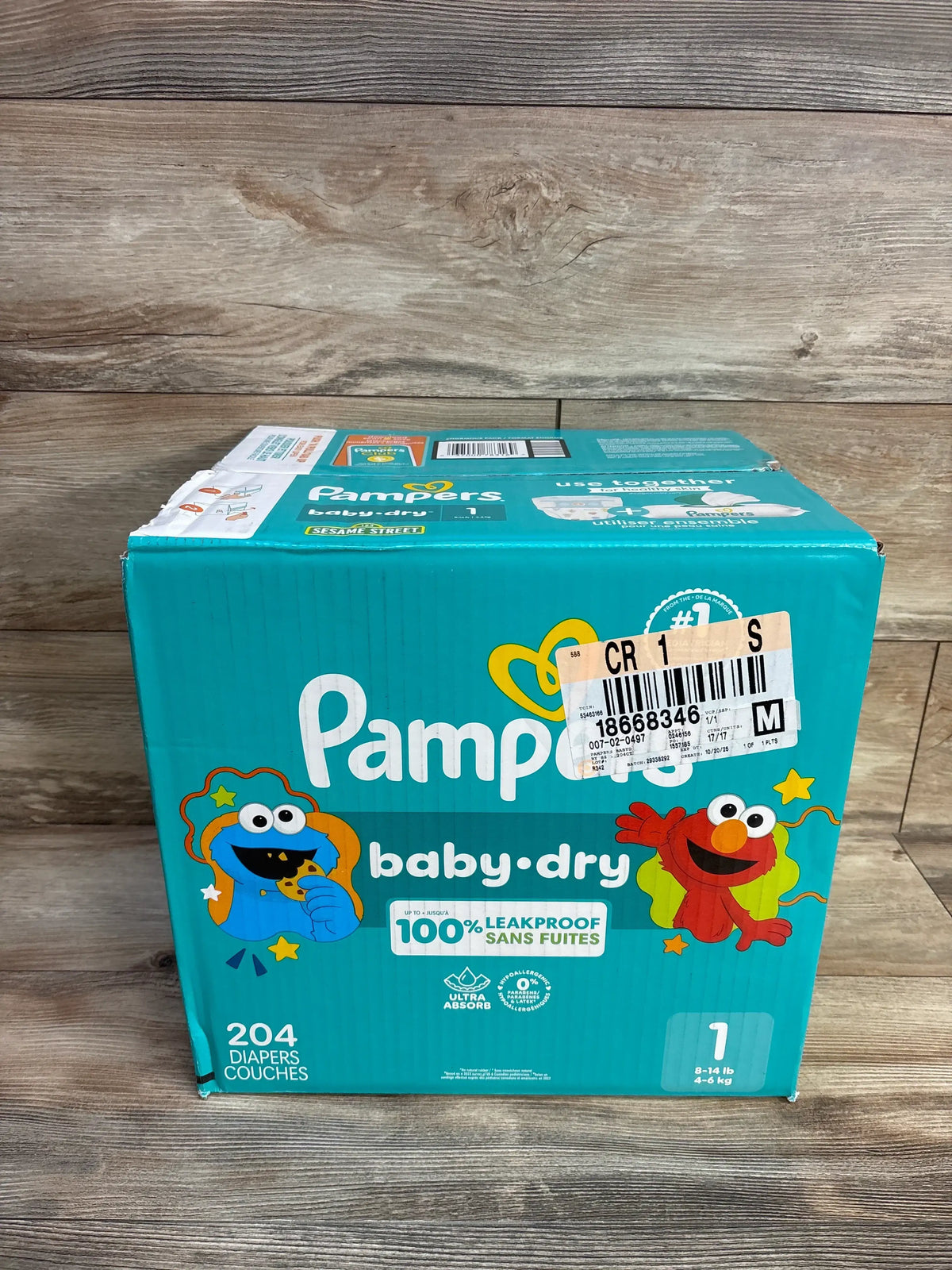 Three-quarter view of Pampers Baby Dry diaper box with 204 diapers, Size 1, Sesame Street characters, and 100% leakproof label