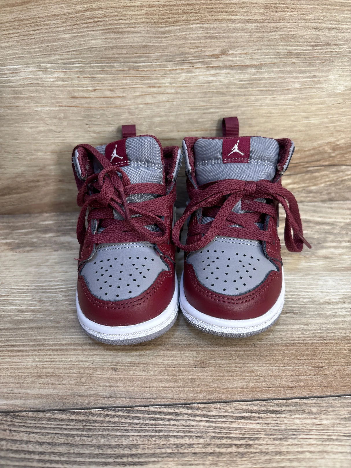 Front view of Air Jordan 1 Mid TD 'Cherrywood Red' sneakers showing maroon and gray high-top leather, Jumpman logo on wood
