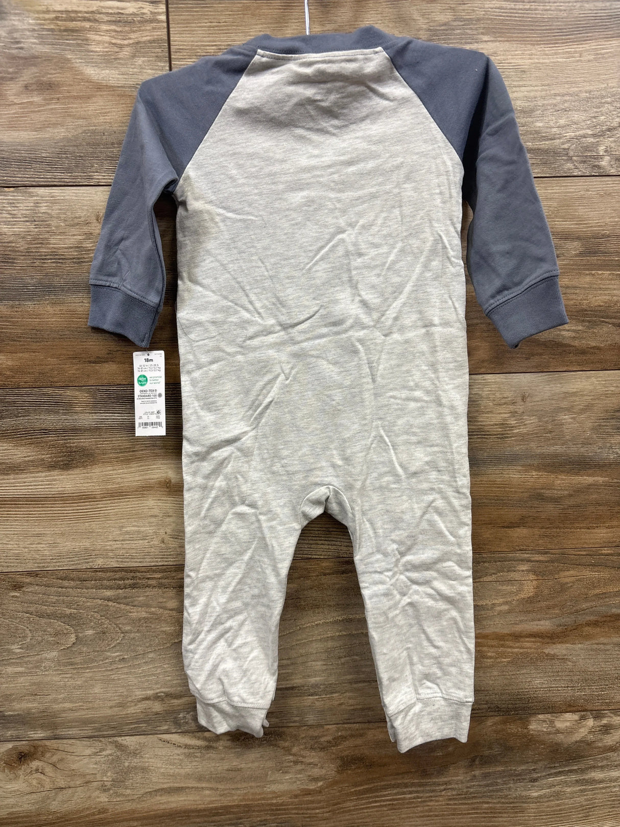 Infant gray and charcoal long sleeve romper with tag, laid on wood background
