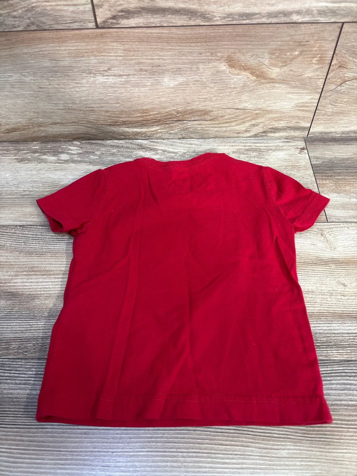Back view of Jordan Jumpman logo shirt in red, showing short sleeves and relaxed cut on a wood-look floor