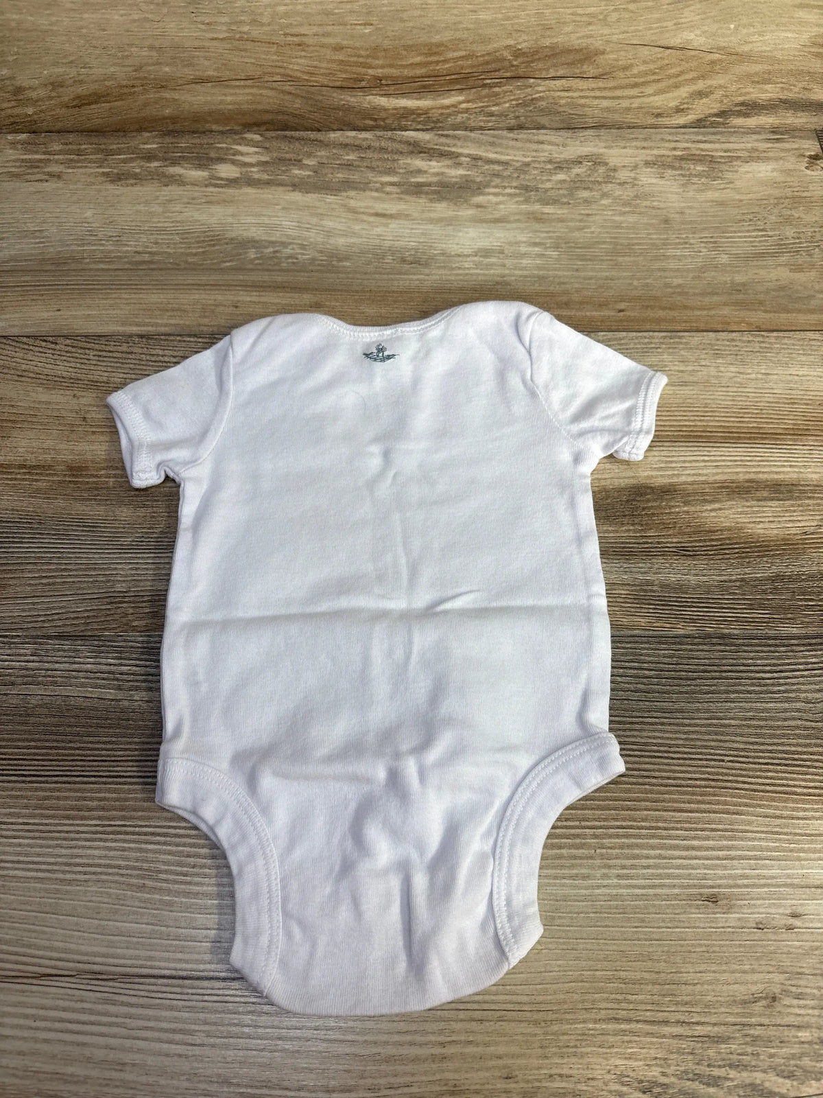 Front view of Bella Baby Ooooh La La bodysuit in white, showcasing short sleeves with a wood-grain background