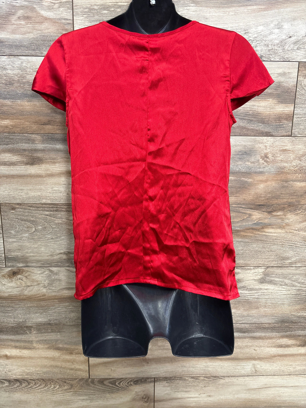Red short sleeve girls blouse on mannequin with wood background
