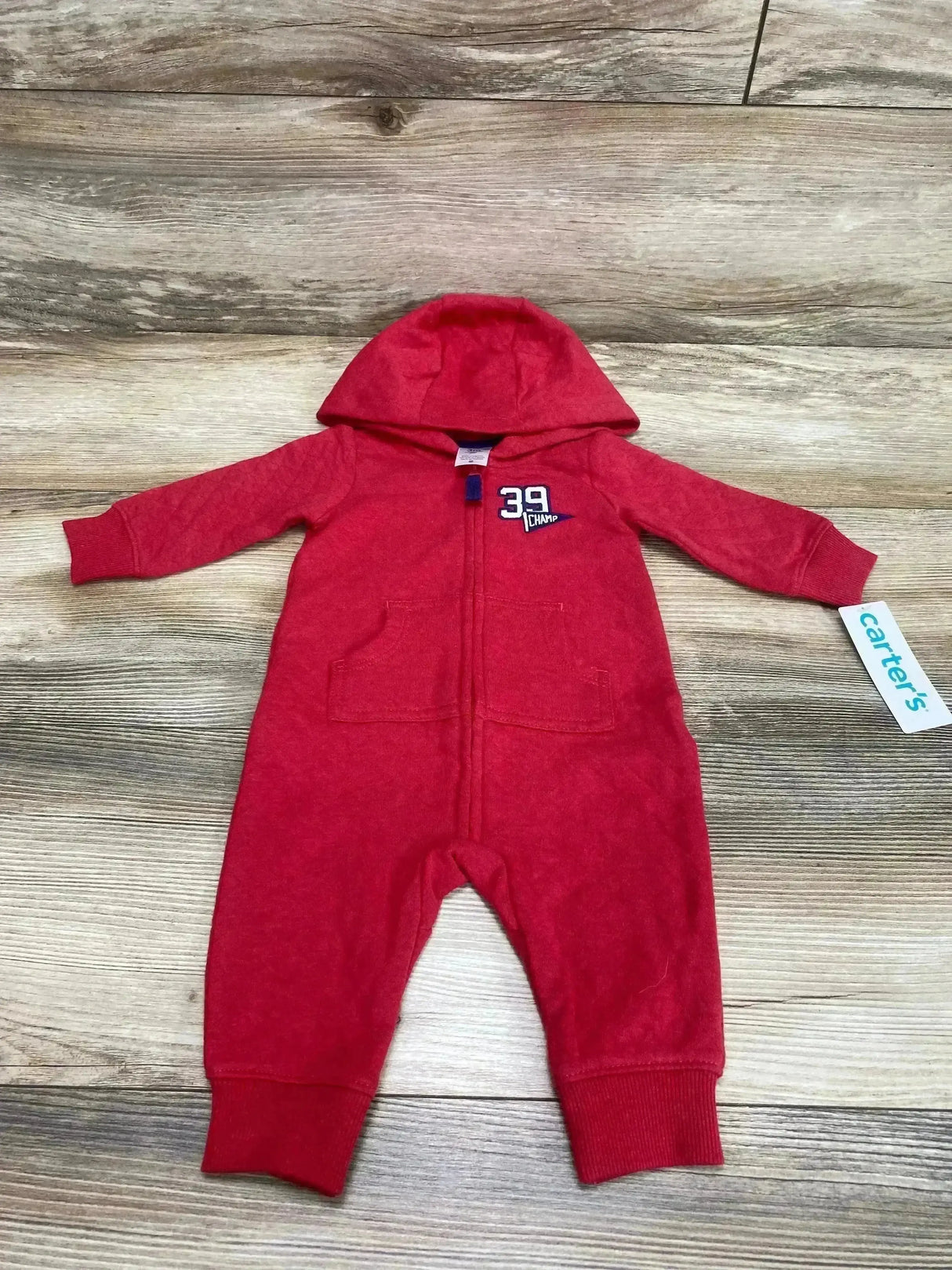 Front view of Carters red hooded double knit jumpsuit 3M with zipper and pockets and 39 Champ chest logo on wood floor