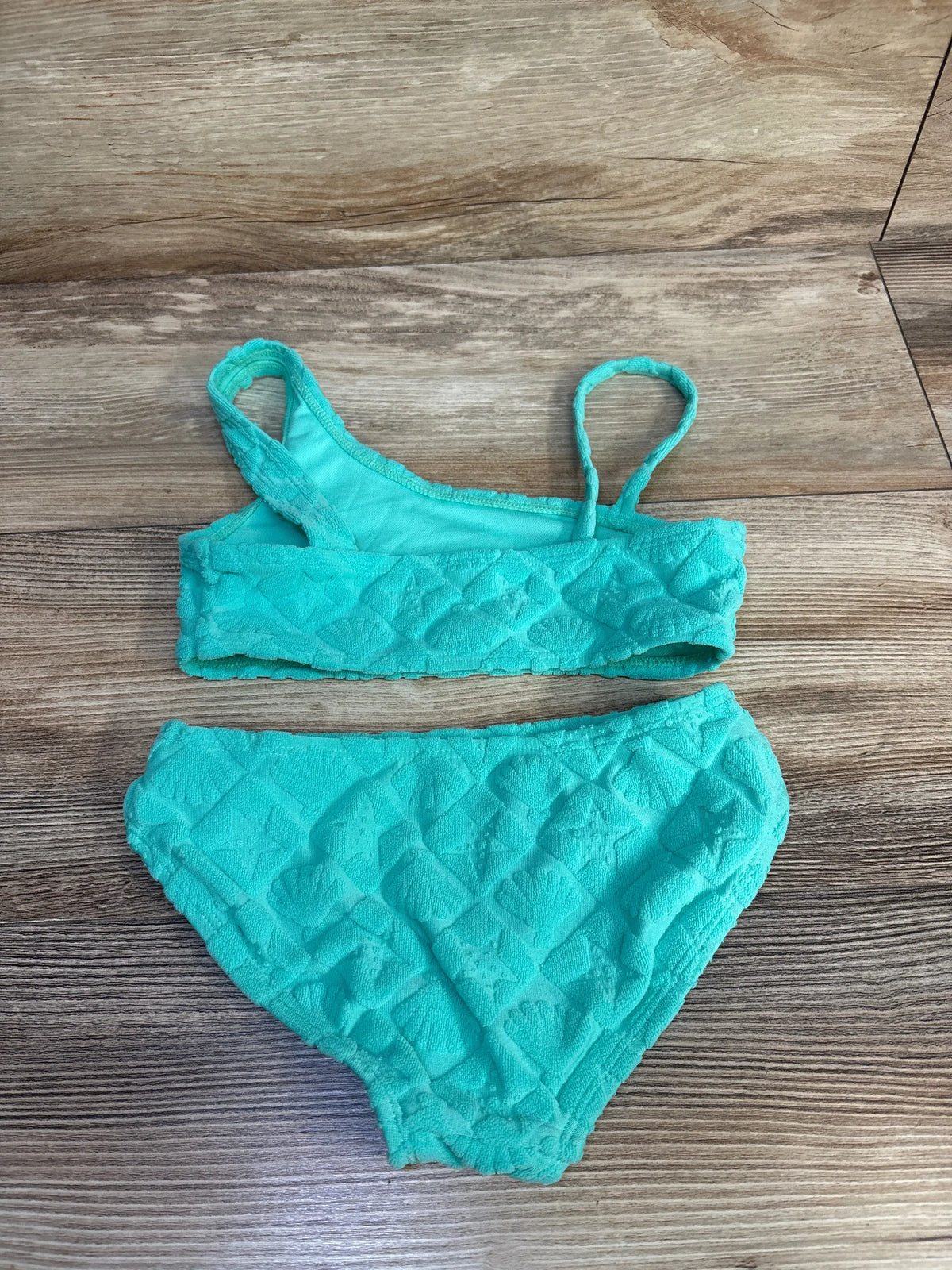 Front view of Cat & Jack teal two-piece terry cloth swimsuit set showcasing textured fabric with wood-grain background