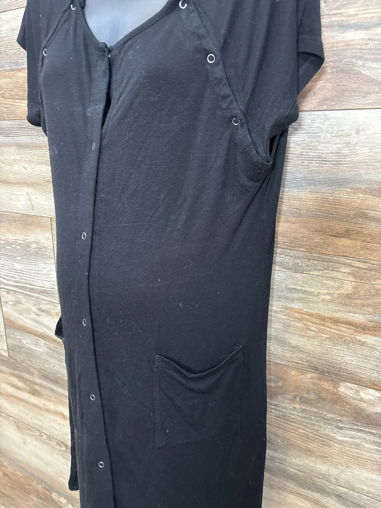 Black maternity dress with front buttons and pocket displayed on mannequin