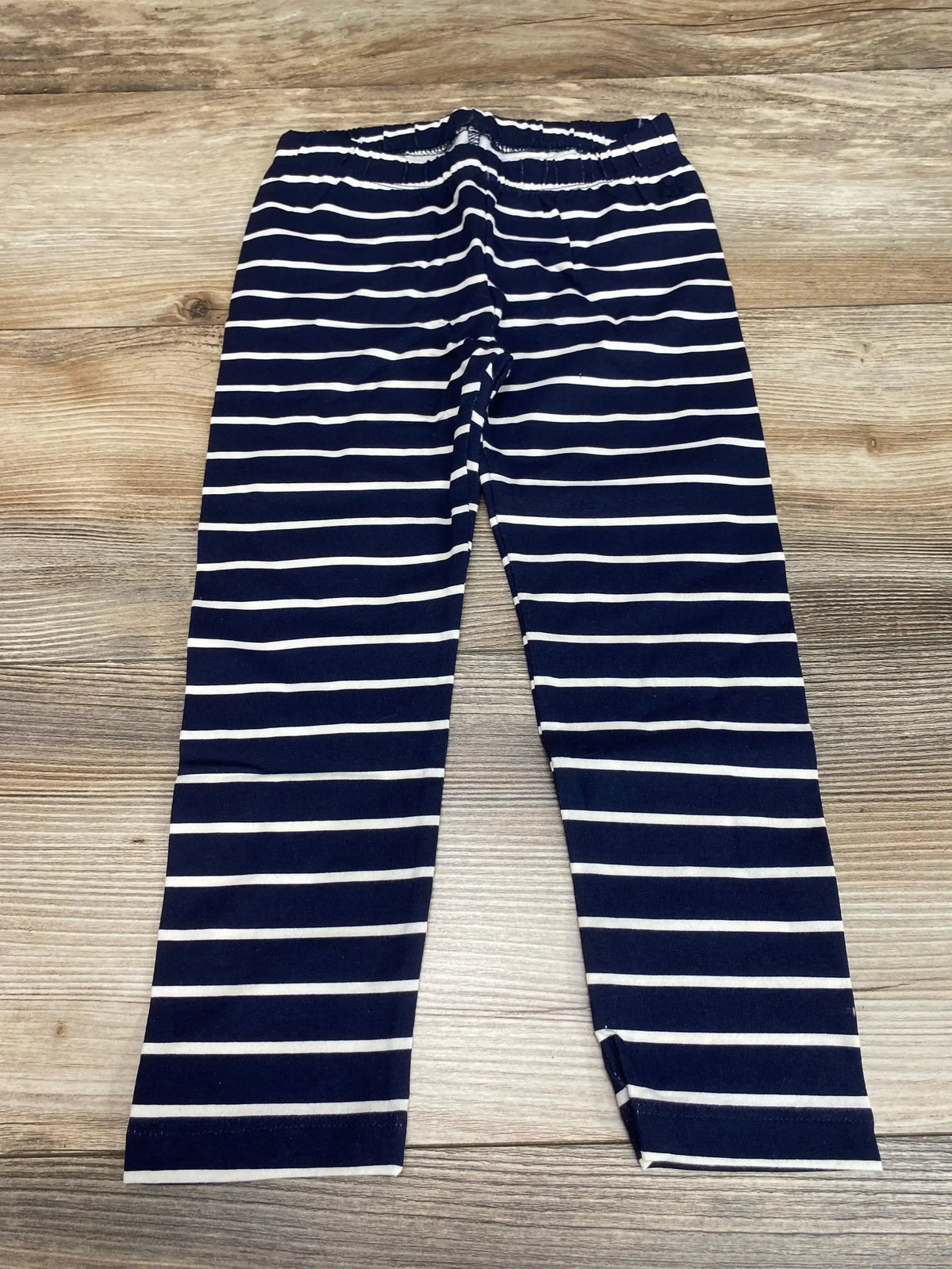 Flat lay of Baby Gap navy and white striped toddler leggings size 3T showing elastic waistband and full-length legs on wood floor background