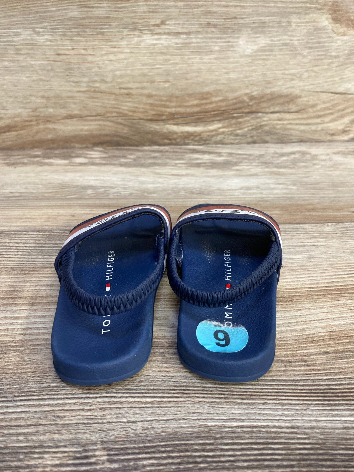 Navy blue Tommy Hilfiger toddler sandals on wood, size 9 sticker visible.