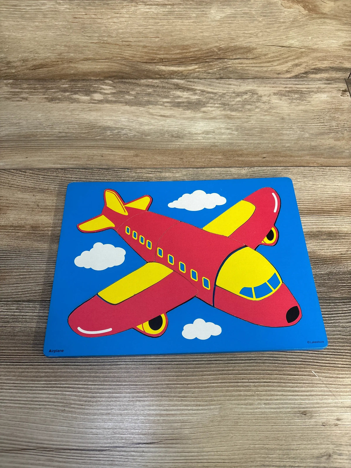 Colorful airplane puzzle with red and yellow plane on blue background and wooden table