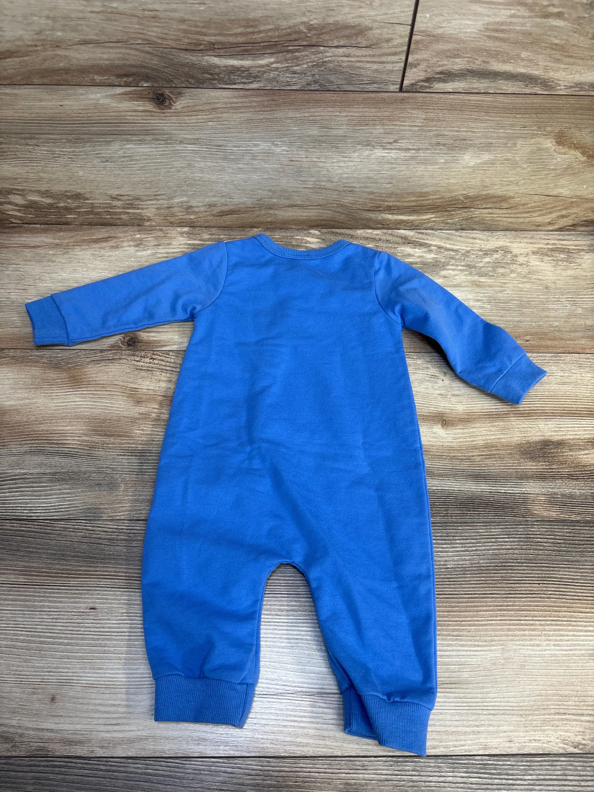 Blue long sleeve baby romper displayed on wooden background