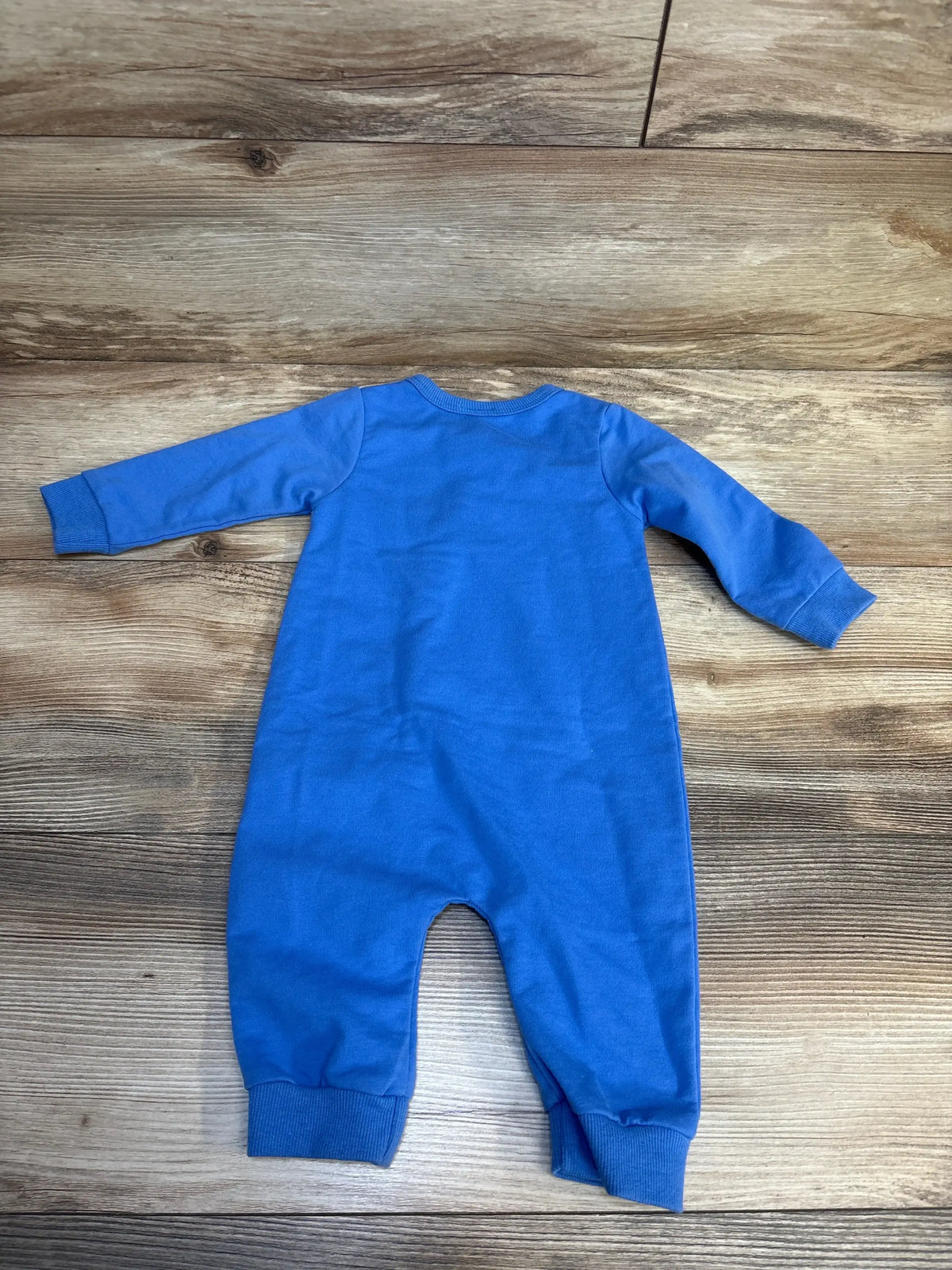 Blue long sleeve baby romper displayed on wooden background