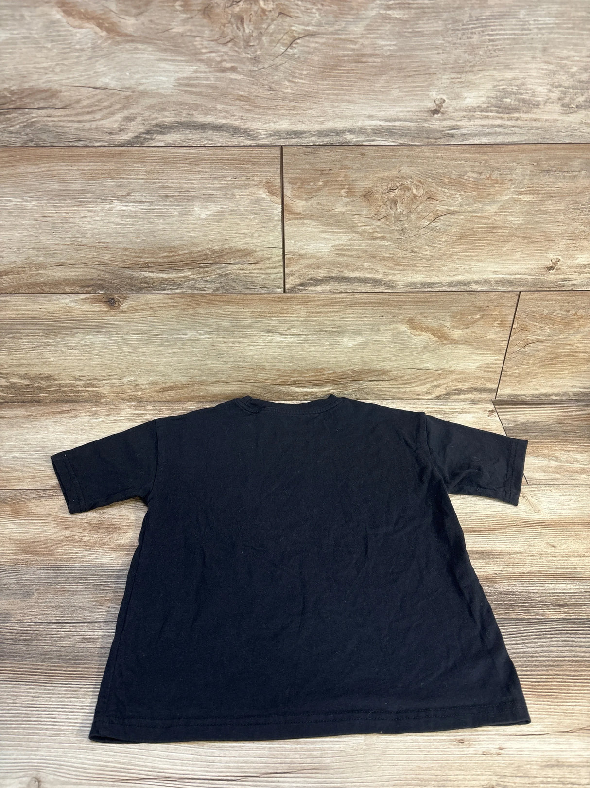 Black kids t-shirt laid flat on wood floor, children's clothing resale