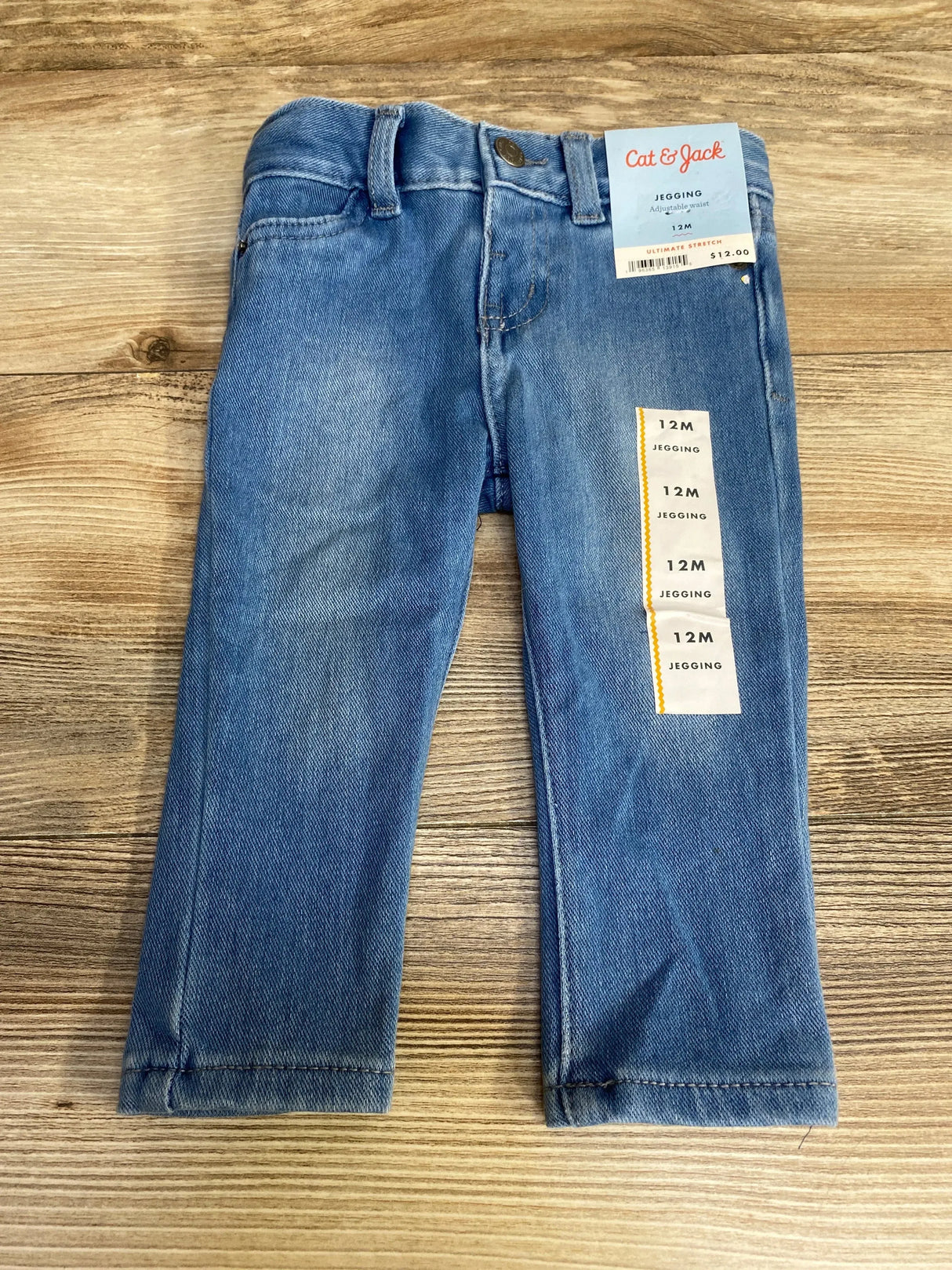 Front view of Cat & Jack blue toddler jeggings showing adjustable waist and light wash on wood floor background