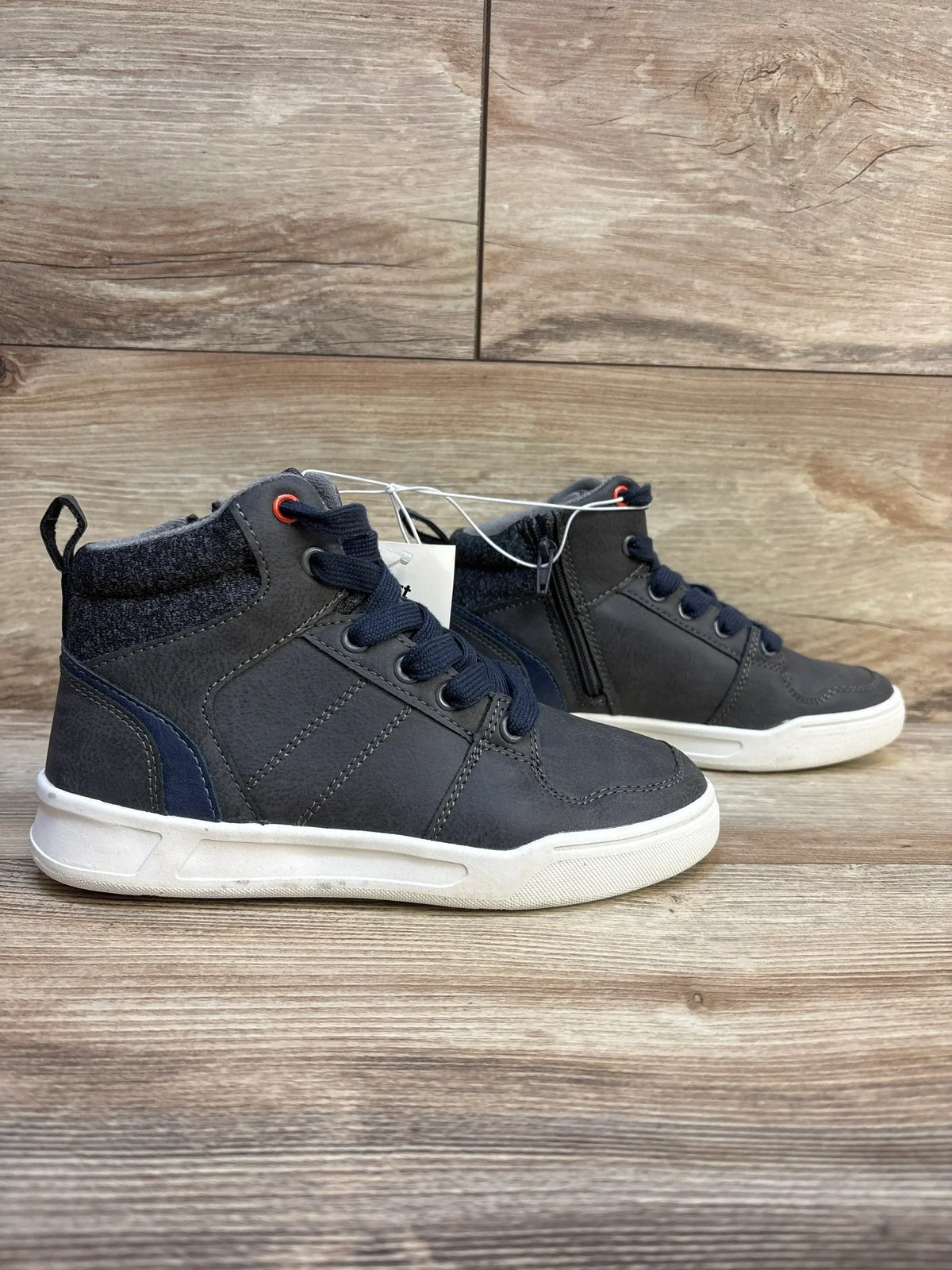 Side view of Art Class Geoff high-top kids sneakers with inner zipper, navy laces, knit ankle cuff, and white soles on wood background