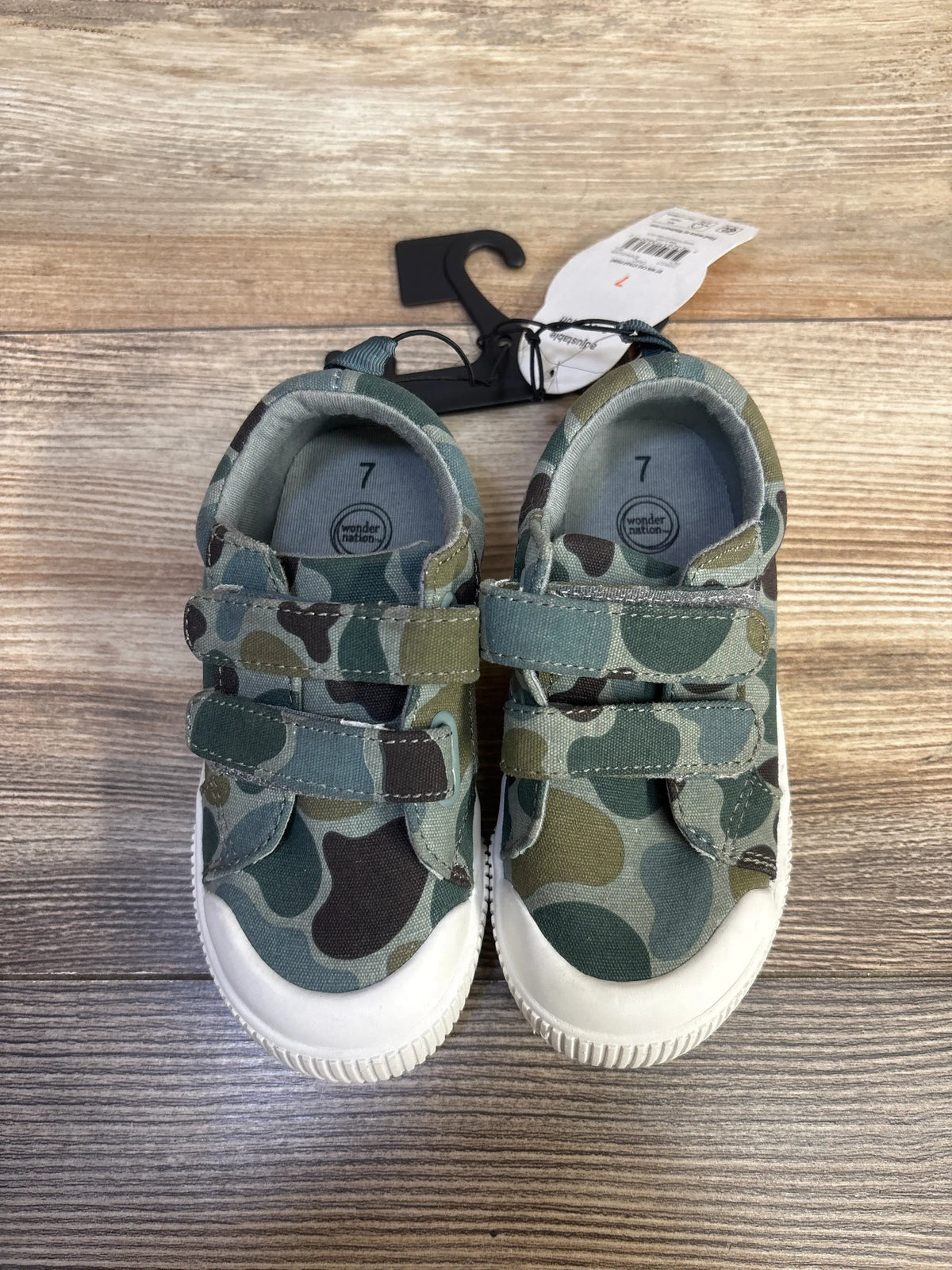 Top view of green Wonder Nation double-strap bump-toe sneakers showing camouflage uppers and two hook-and-loop straps on wood