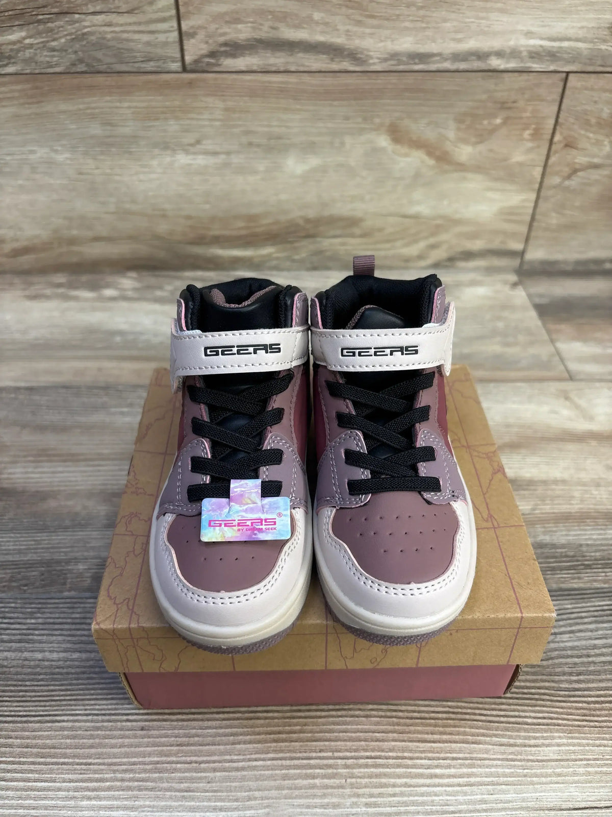 Front view of mauve and white Geers high-top toddler sneakers showcasing Velcro strap with GEERS logo and black laces on a cardboard shoebox on wood floor