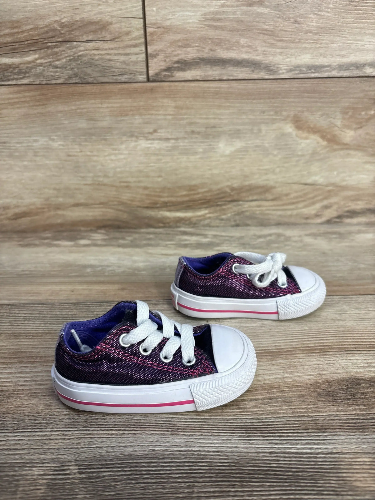Purple glitter toddler sneakers with white laces on wood floor