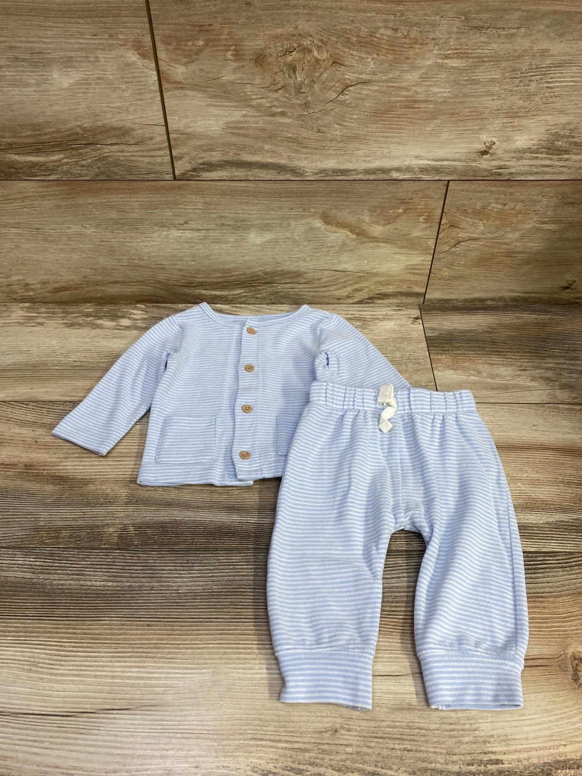 Front view of Child Of Mine blue 2-piece button shirt and pants set showcasing striped fabric and elastic waist on wood floor