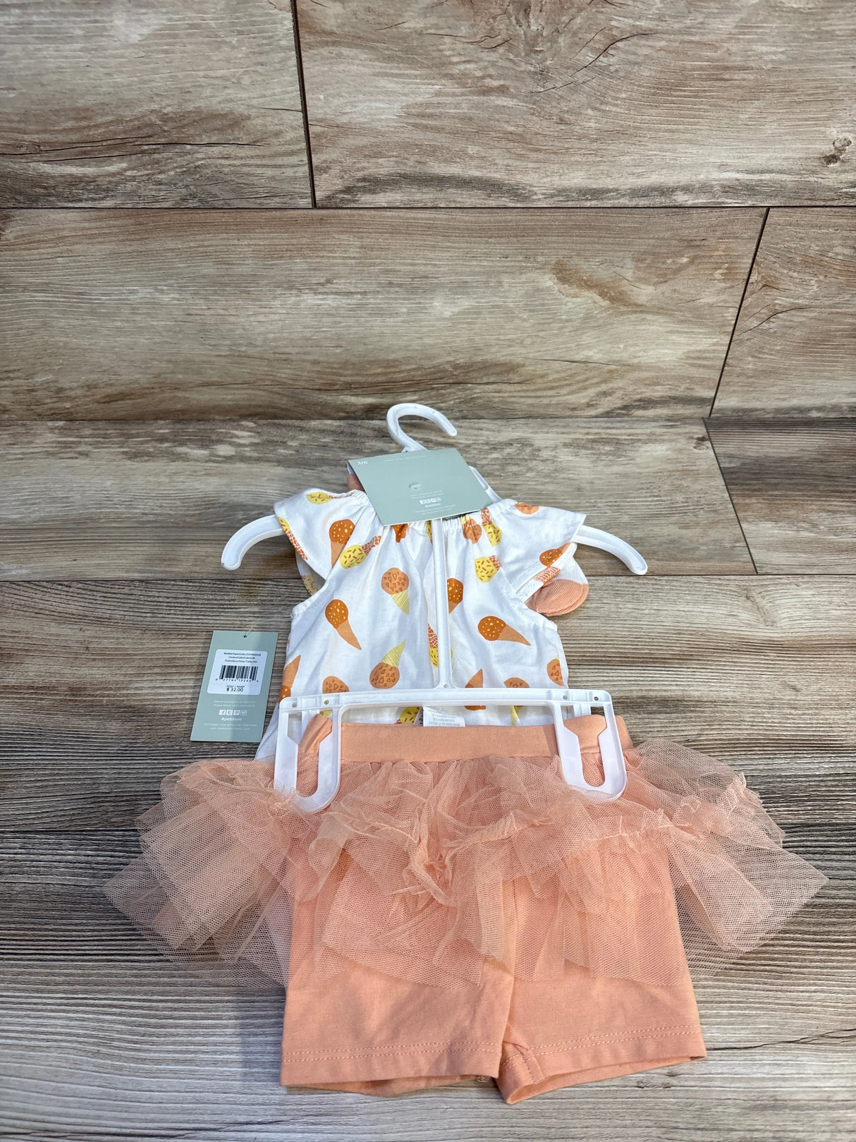 Baby outfit with ice cream print top and peach tutu shorts on hanger