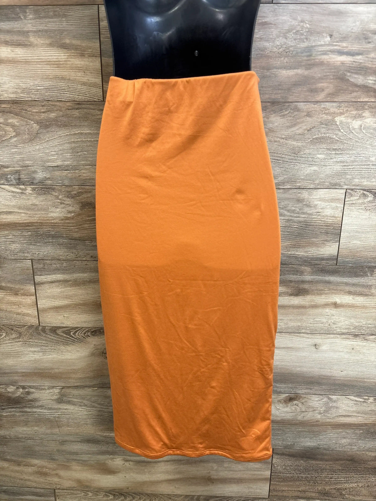 Front view of orange maternity skirt size L showing high elastic waistband and straight midi fit on wood plank background