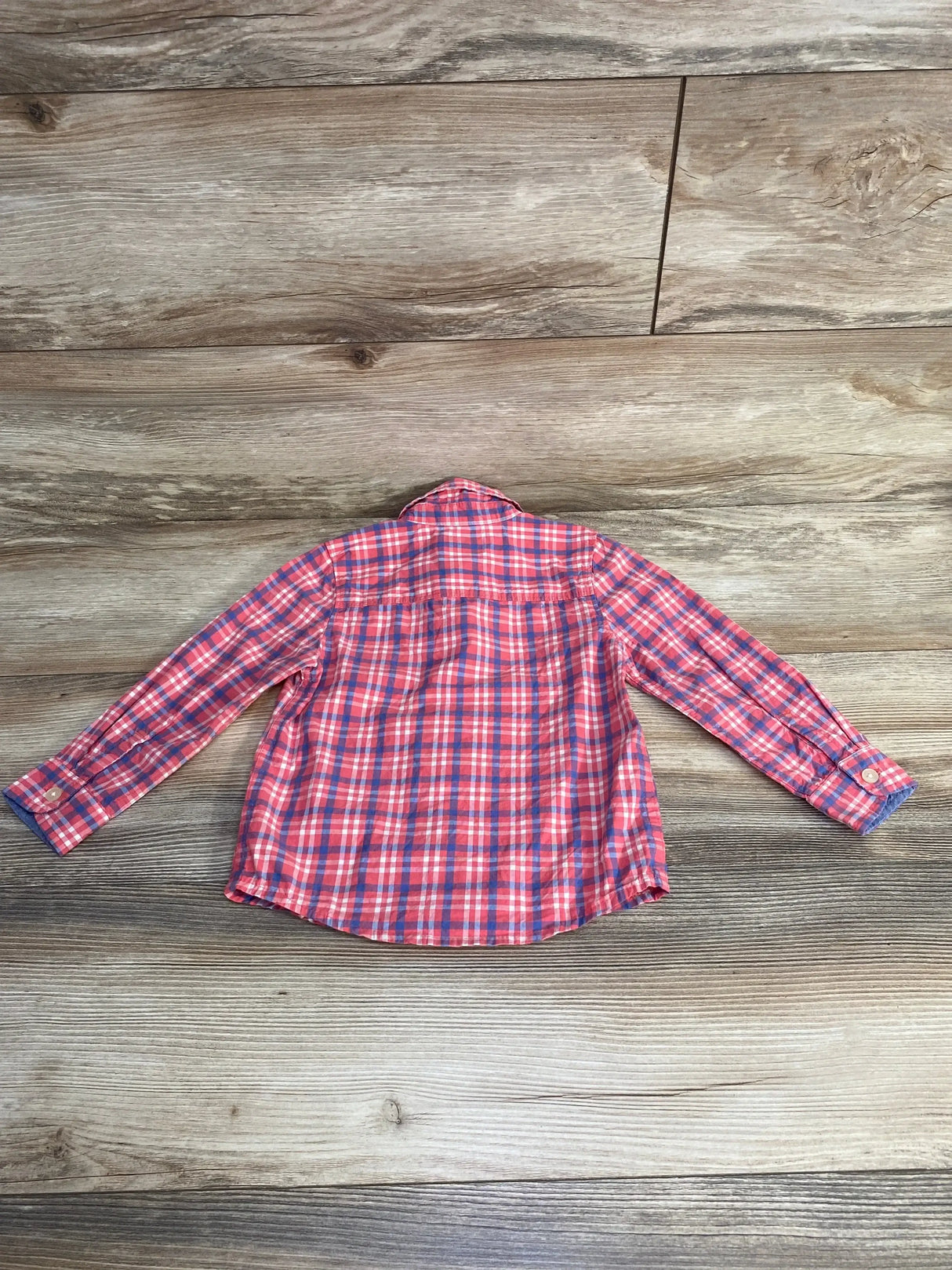 Back view of OshKosh pink and blue plaid toddler button-up shirt (3T) showing long sleeves and button cuffs on wood floor background