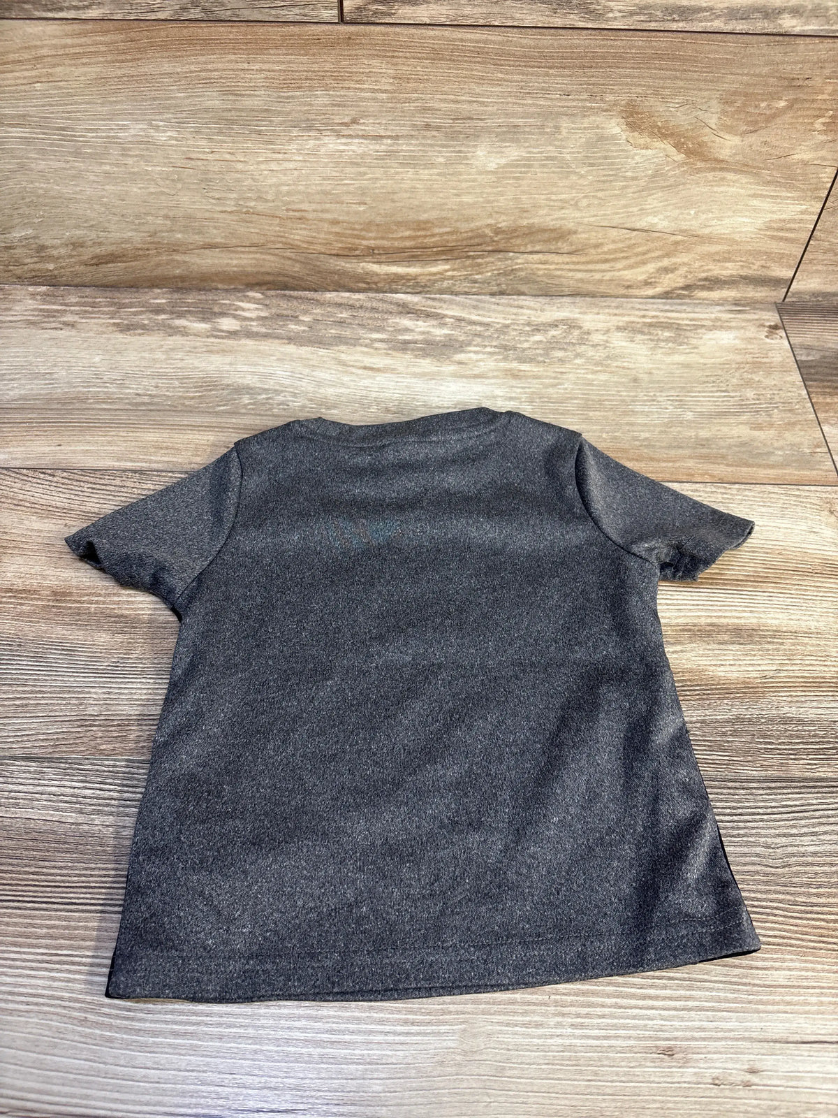 Back view of a grey Puma shirt for baby size 12 months on a wooden background