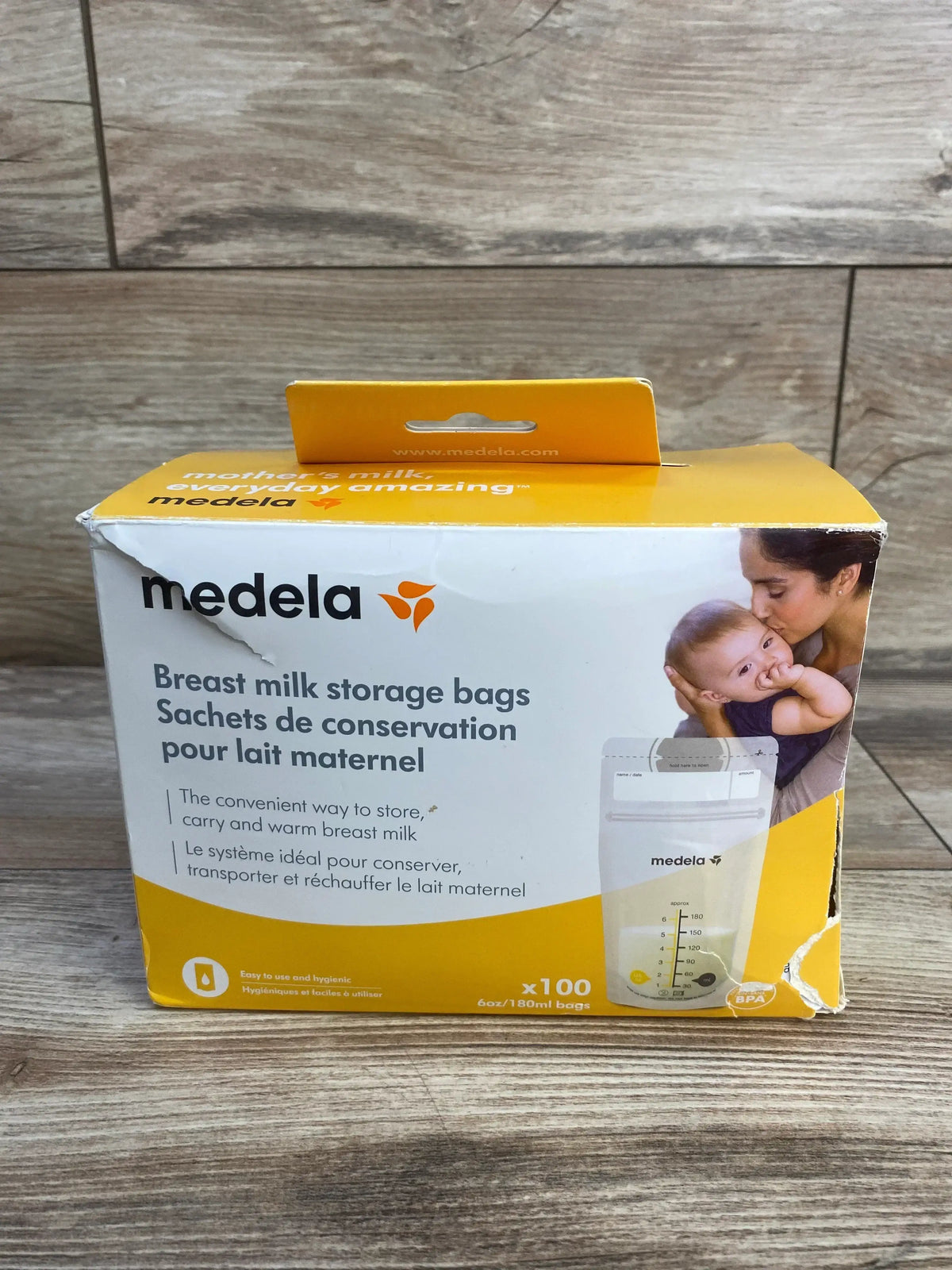 Front view of Medela breast milk storage bags 100-count box showing branding and 6 oz 180 ml markings on wooden surface
