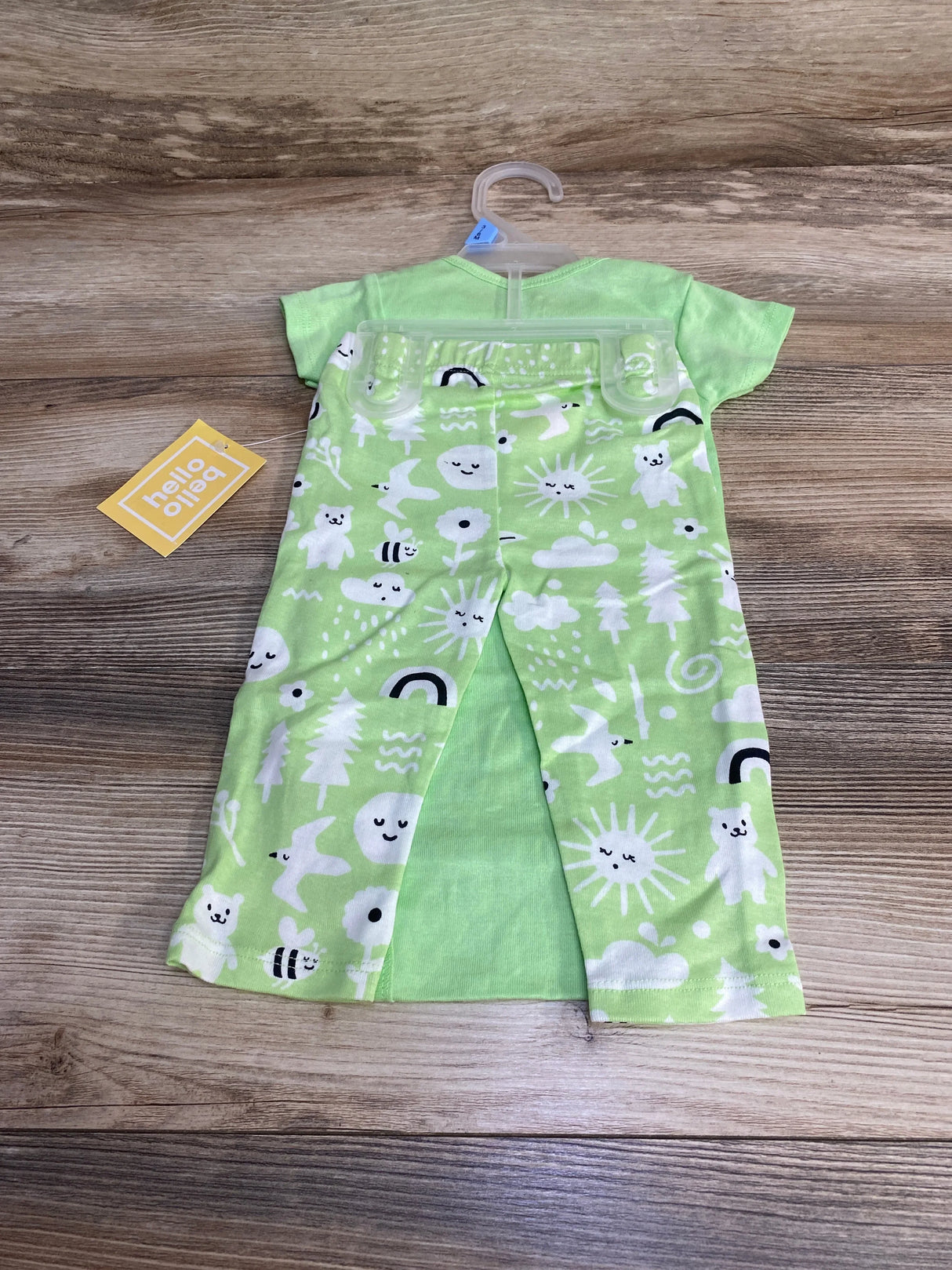 Flat lay of 2pc green Hello Bello bodysuit and pants with white sun, bear and rainbow print on wood