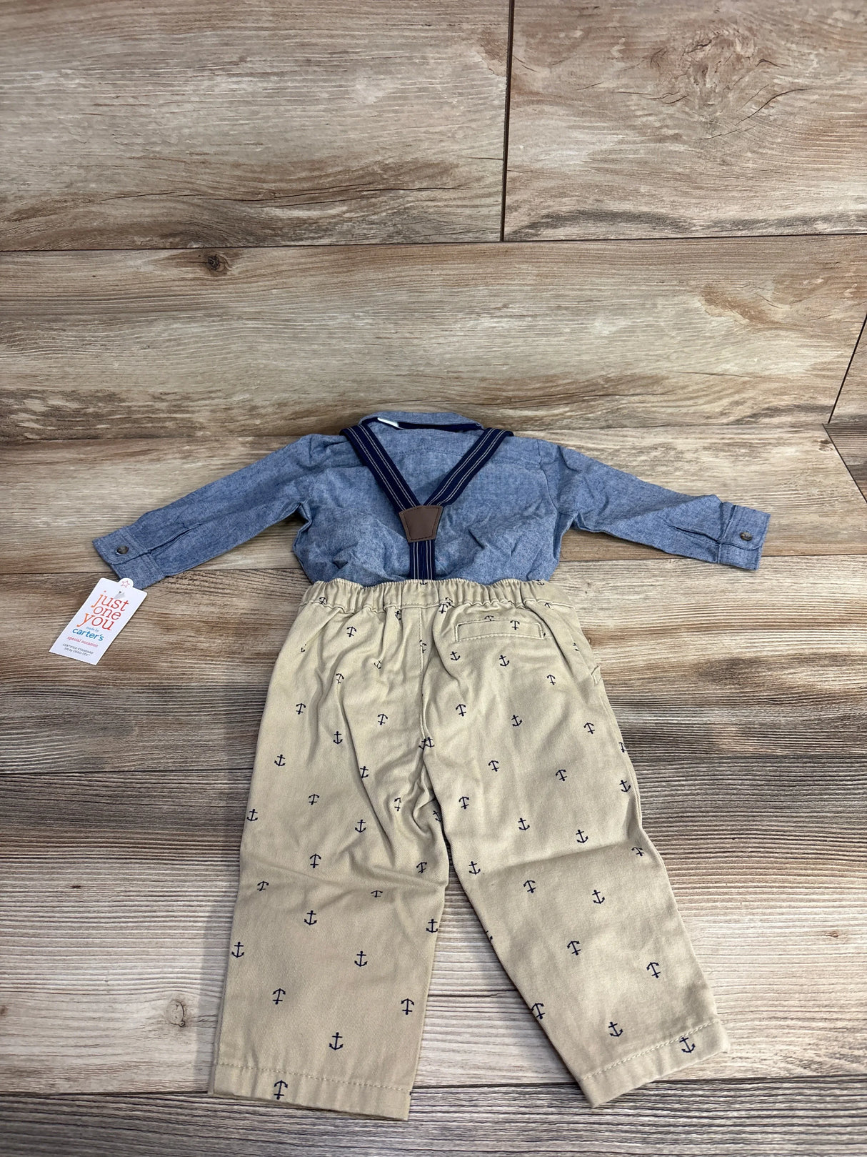 Baby boy nautical outfit with blue shirt, khaki anchor pants, and suspenders on wood floor